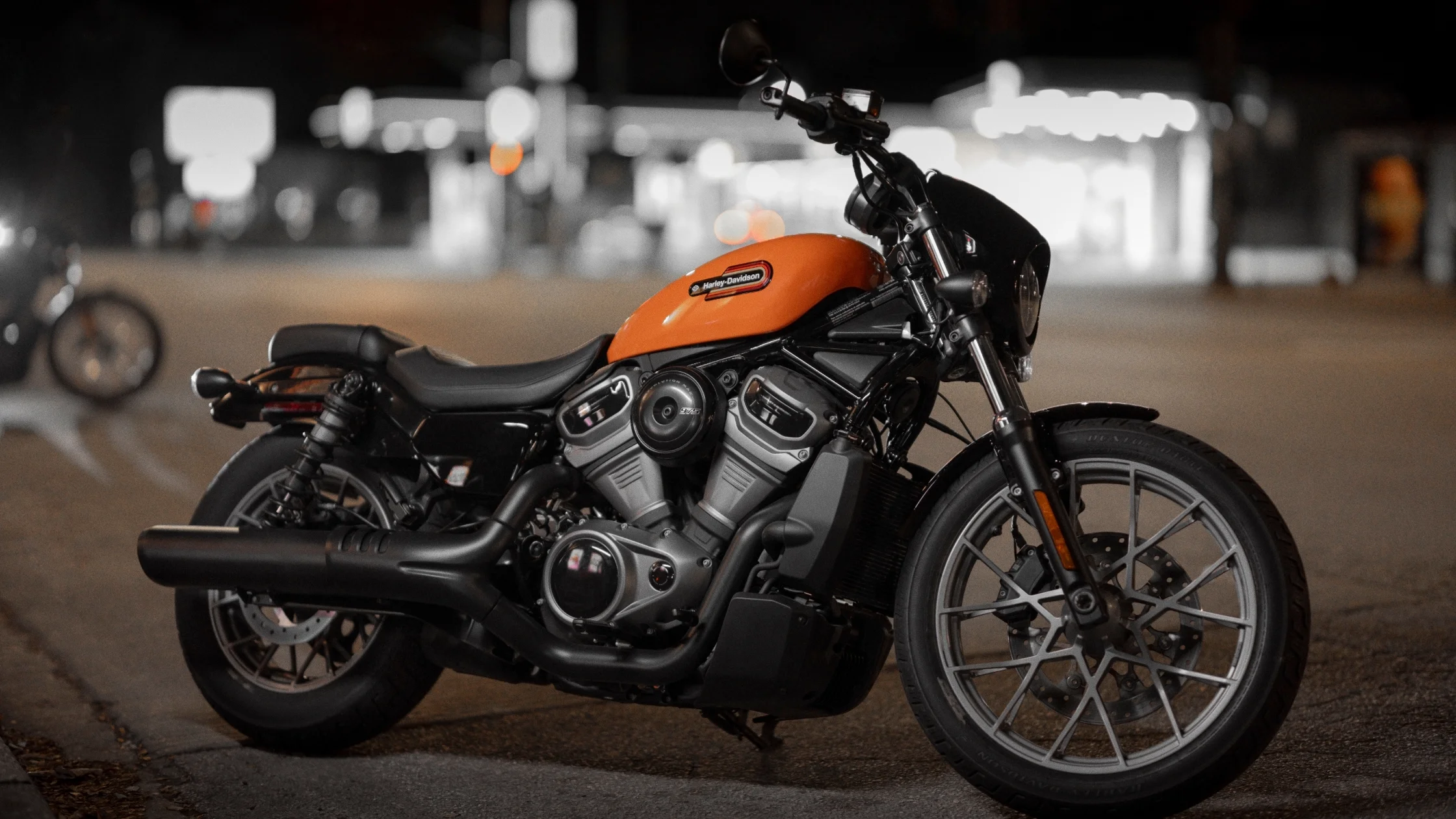 2024 Nightster Special in vivid orange, parked under urban night lights.