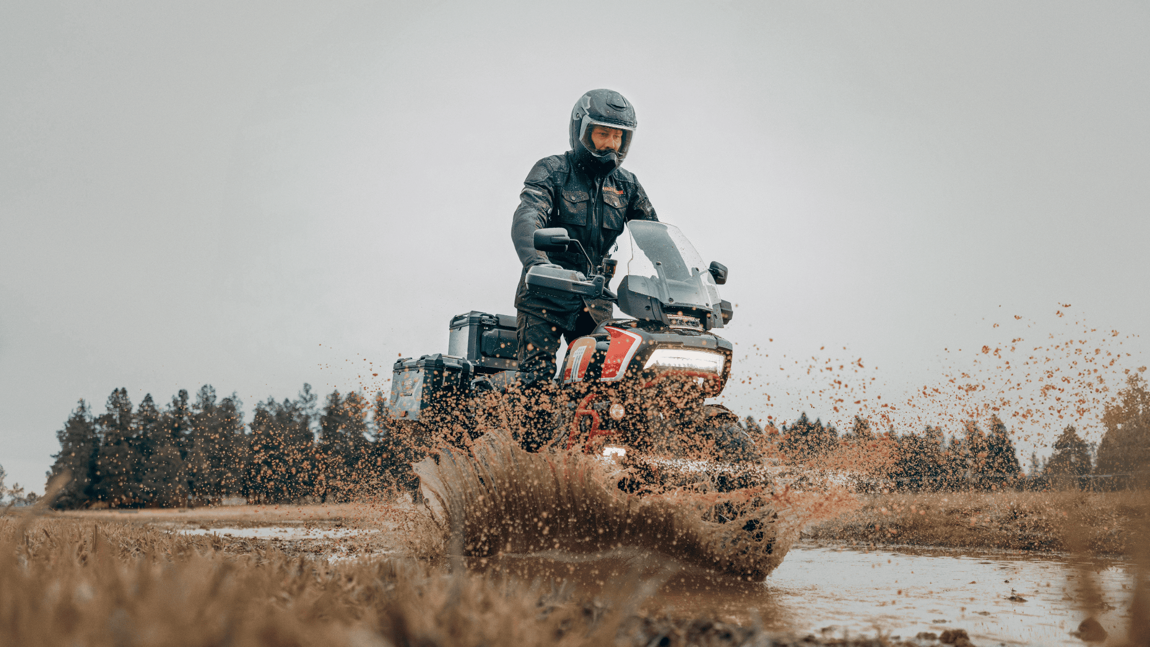A rider tackling muddy terrain on a 2024 Harley-Davidson® CVO™ Pan America® adventure bike in action