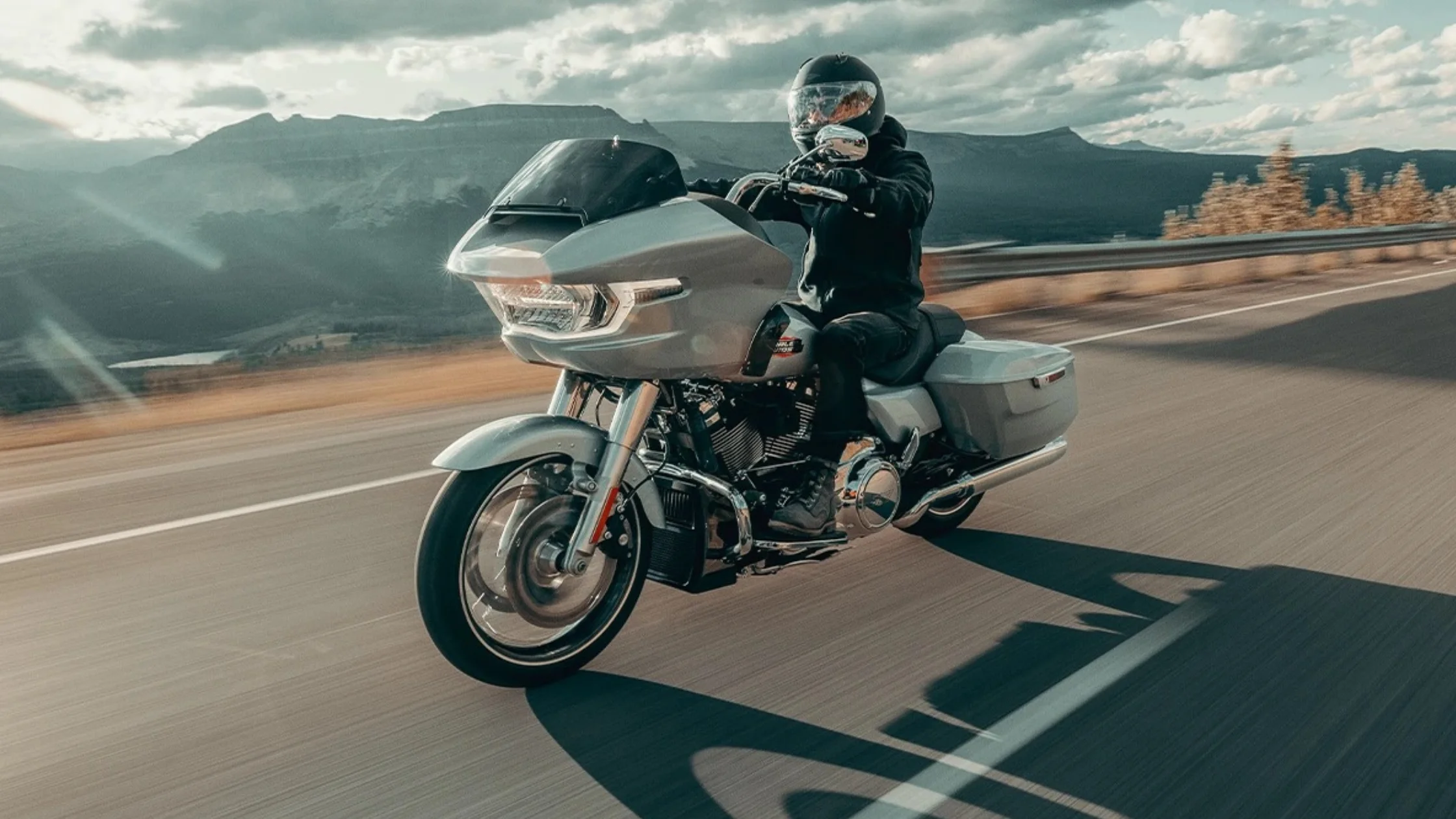 Rider on a Harley-Davidson Road Glide touring motorcycle on a scenic highway.