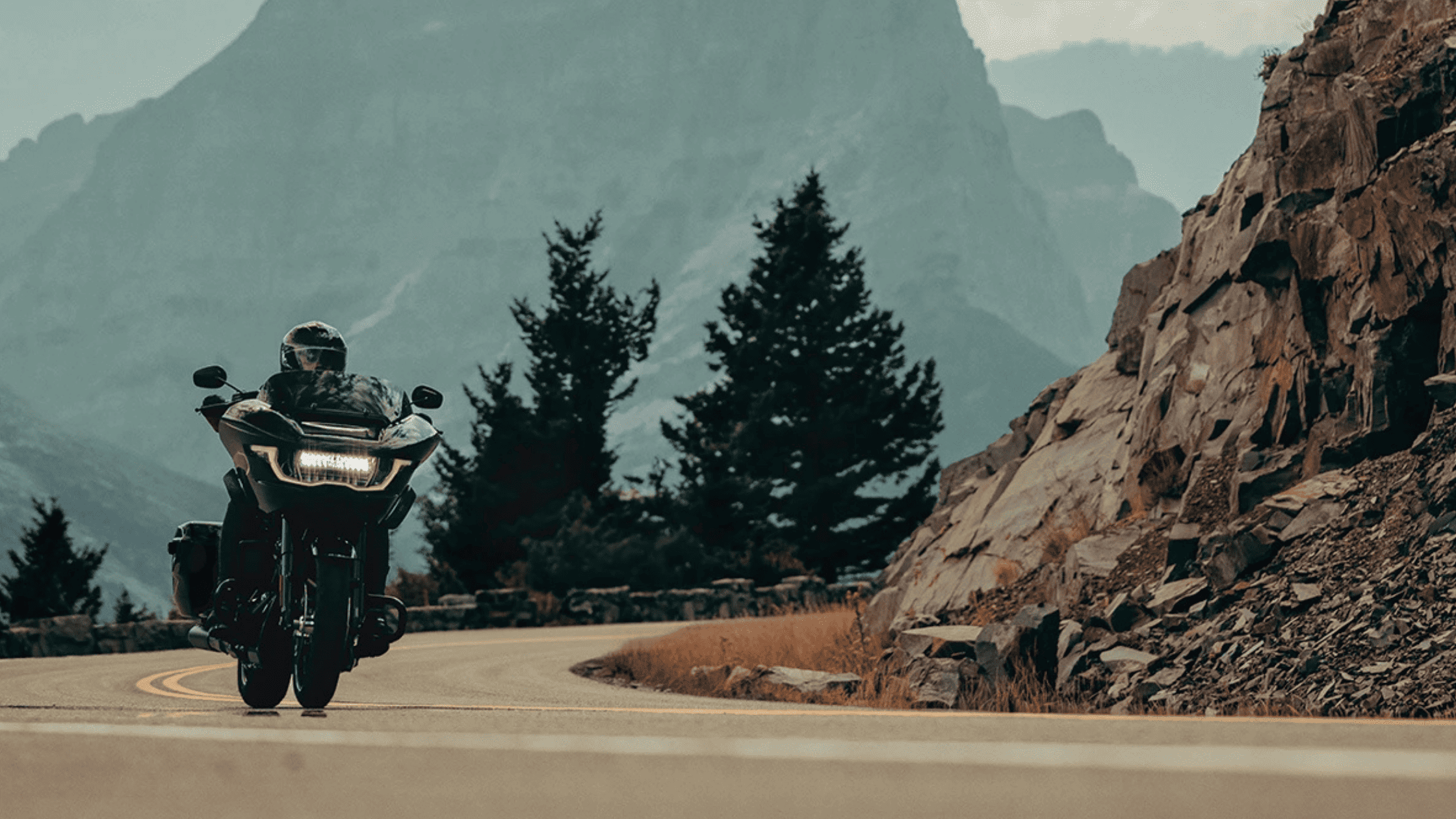 A rider on a 2025 Harley-Davidson® Grand American Touring Motorcycle cruising a scenic mountain road