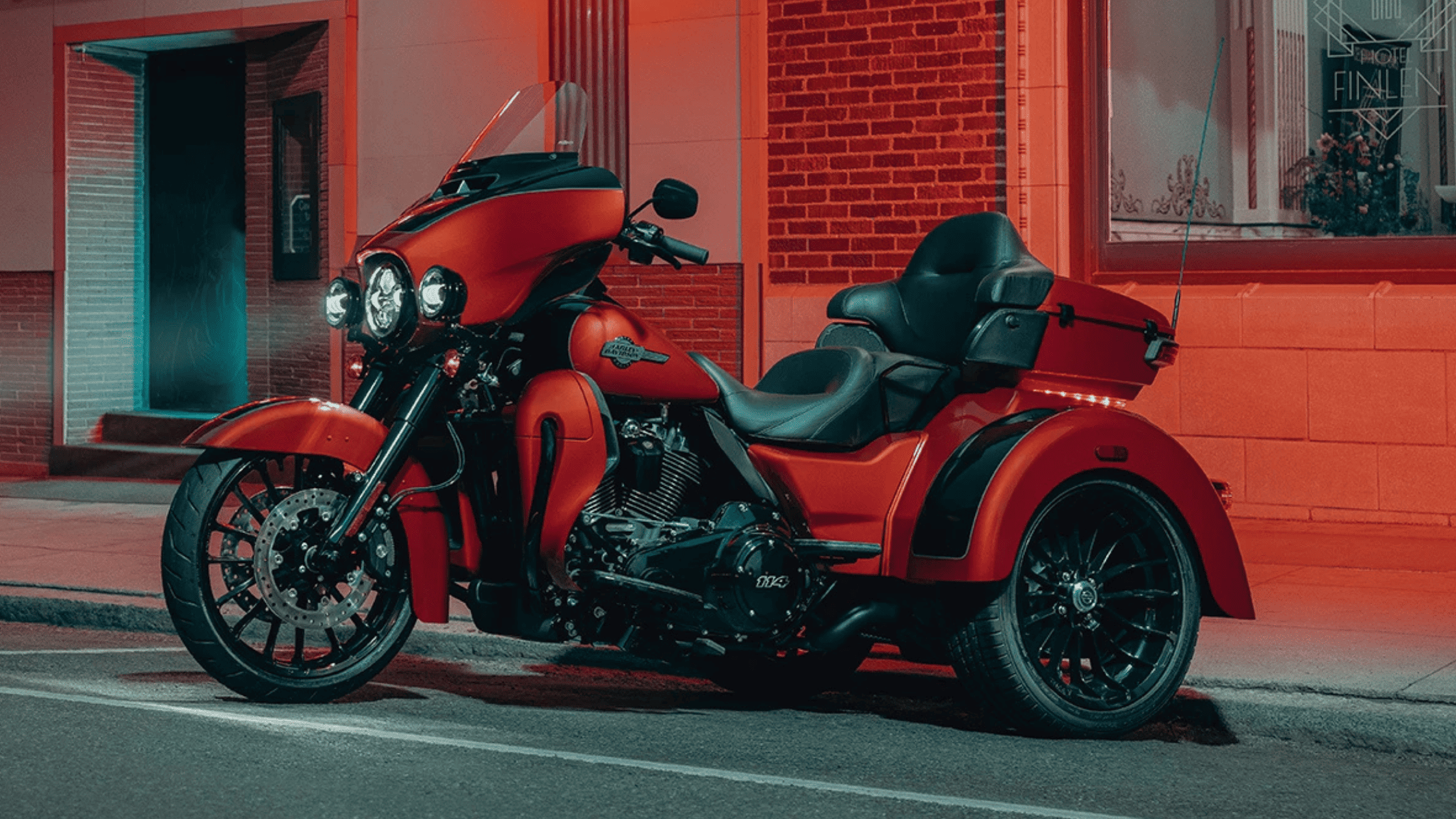 A rider on a 2025 Harley-Davidson® Tri Glide® Ultra navigating a scenic mountain road with sharp curves