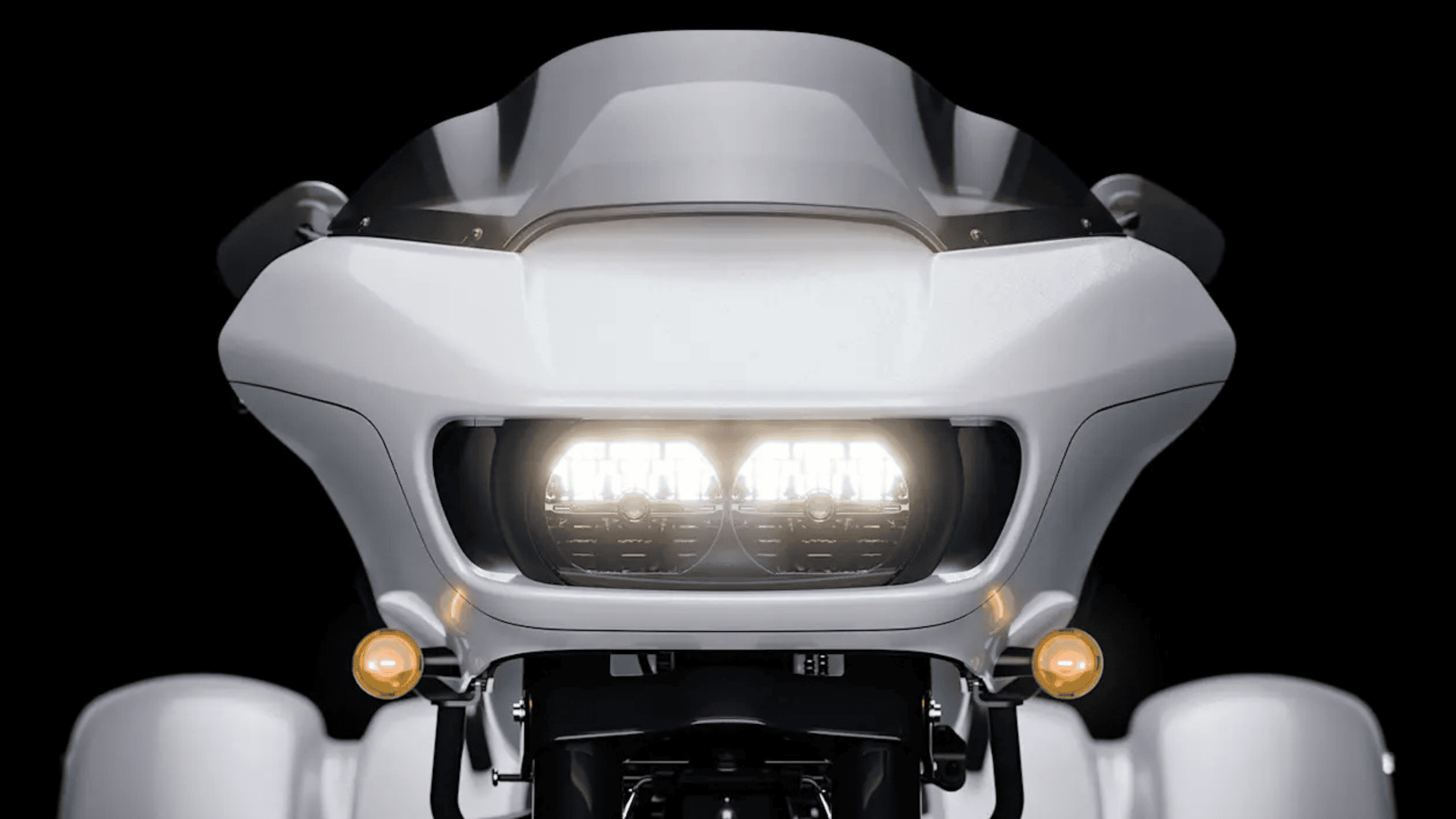 Front view of a sleek motorcycle fairing, twin LED headlights glowing brightly.