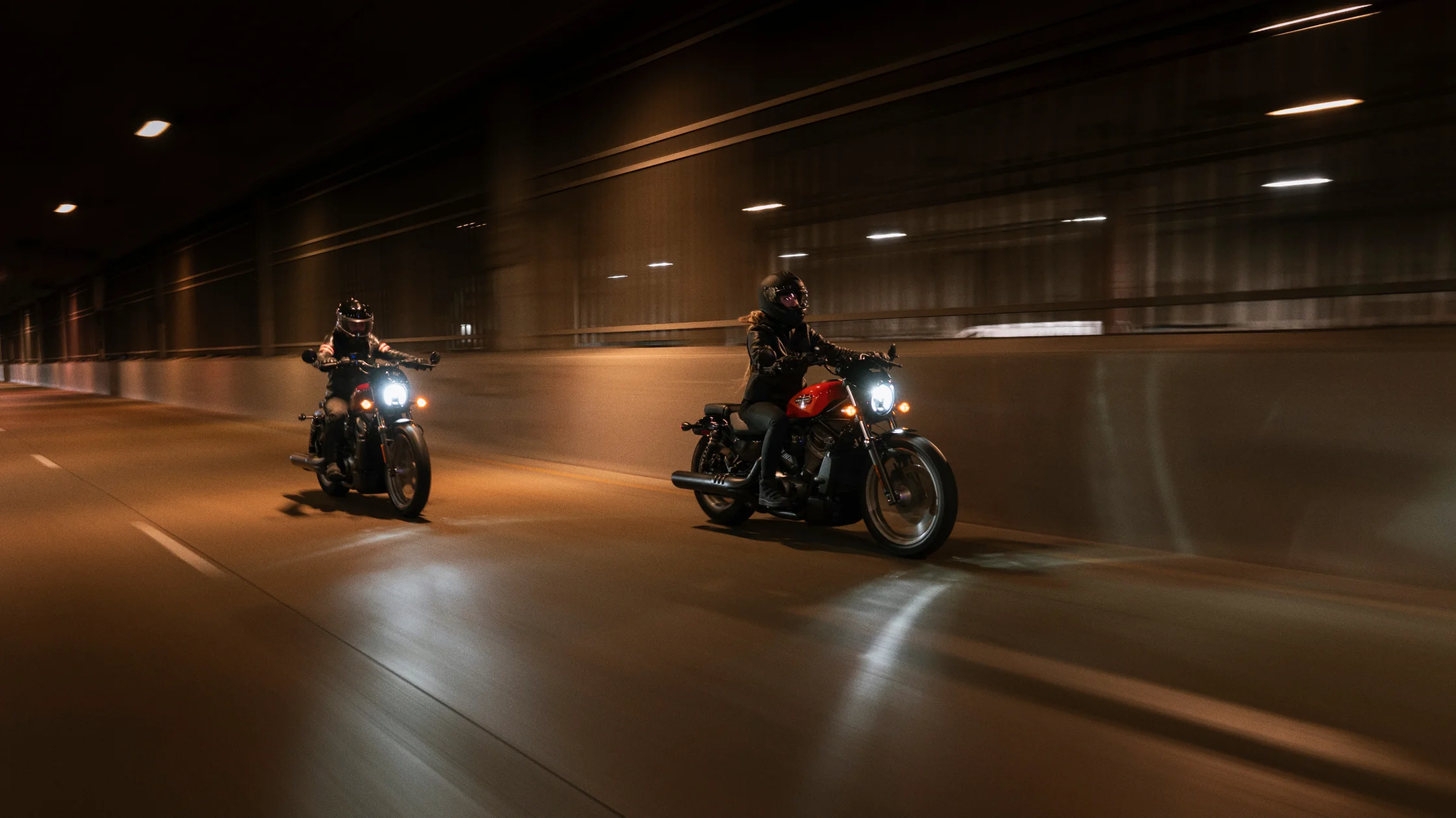 Two motorcyclists riding 2024 Nightster® Special bikes through an illuminated tunnel.