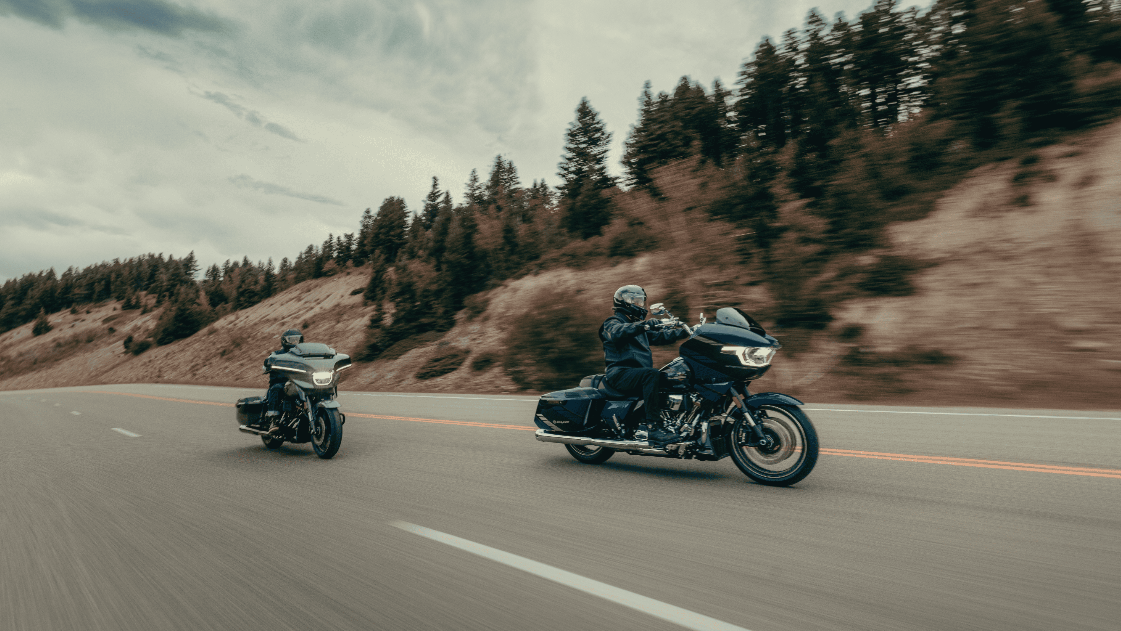 Two touring motorcycles cruising on a scenic highway road.