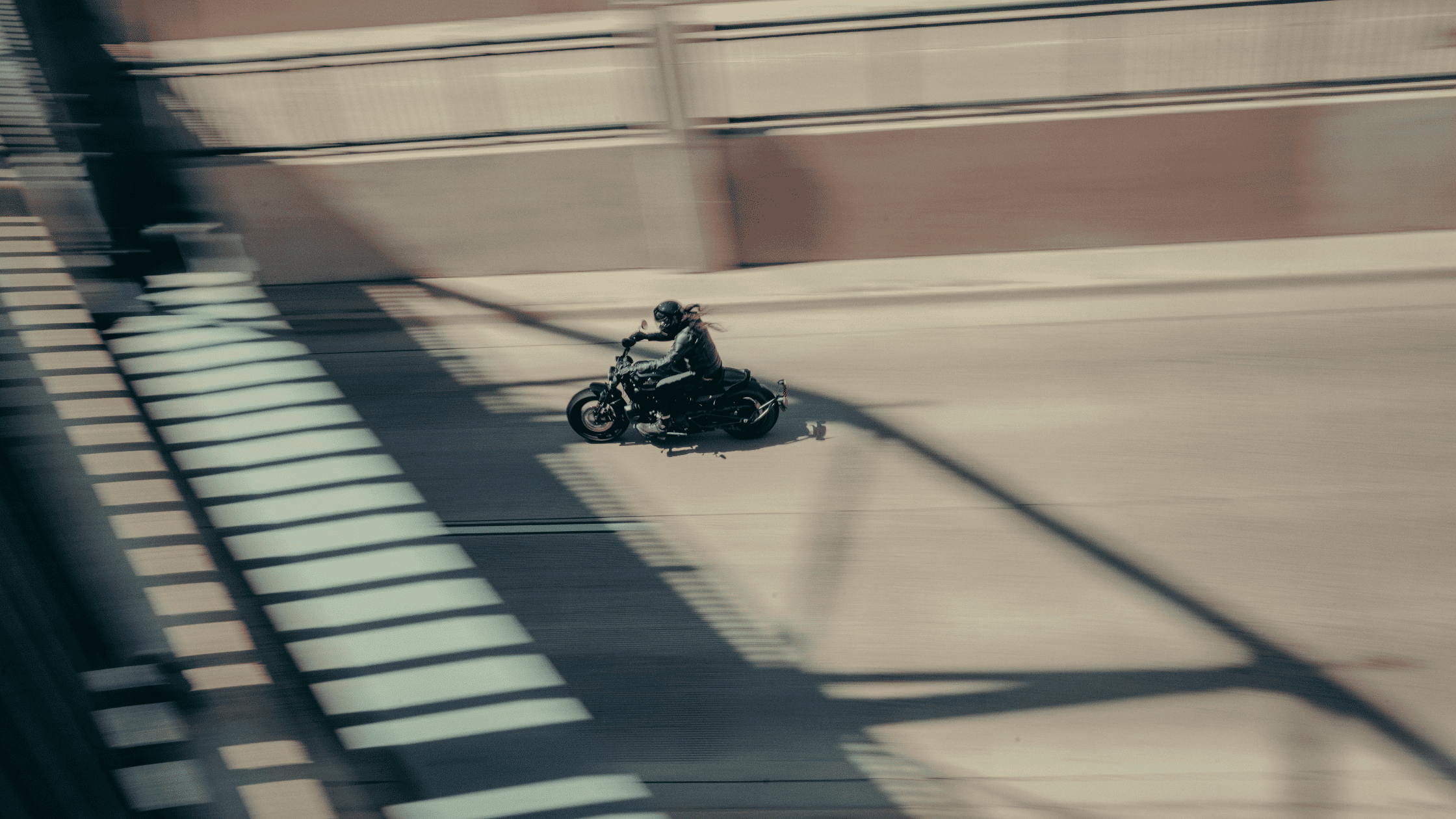 Motorcyclist speeding across a bridge with motion blur effect.