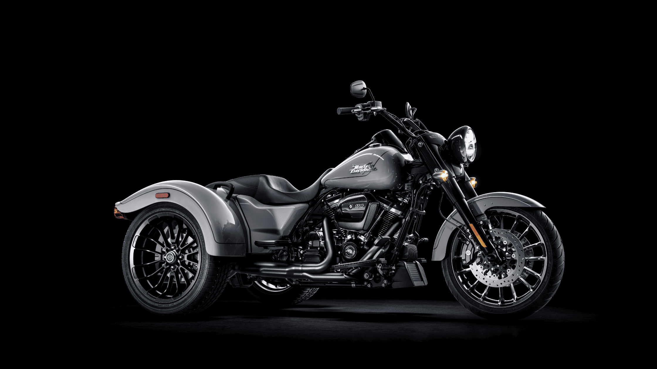 Black and gray trike motorcycle showcased against a dark background.