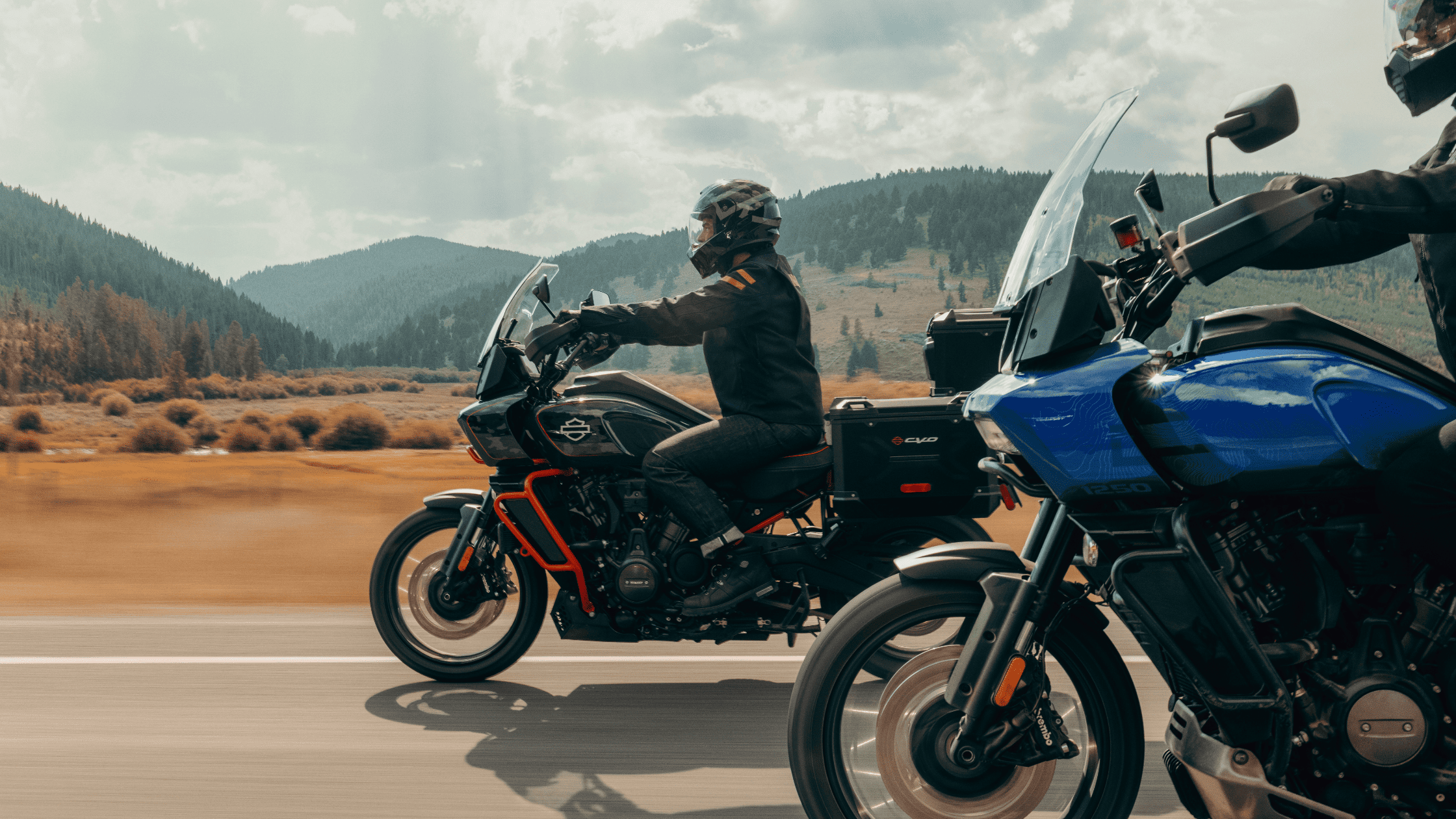Two adventure motorcyclists riding side by side on a highway.