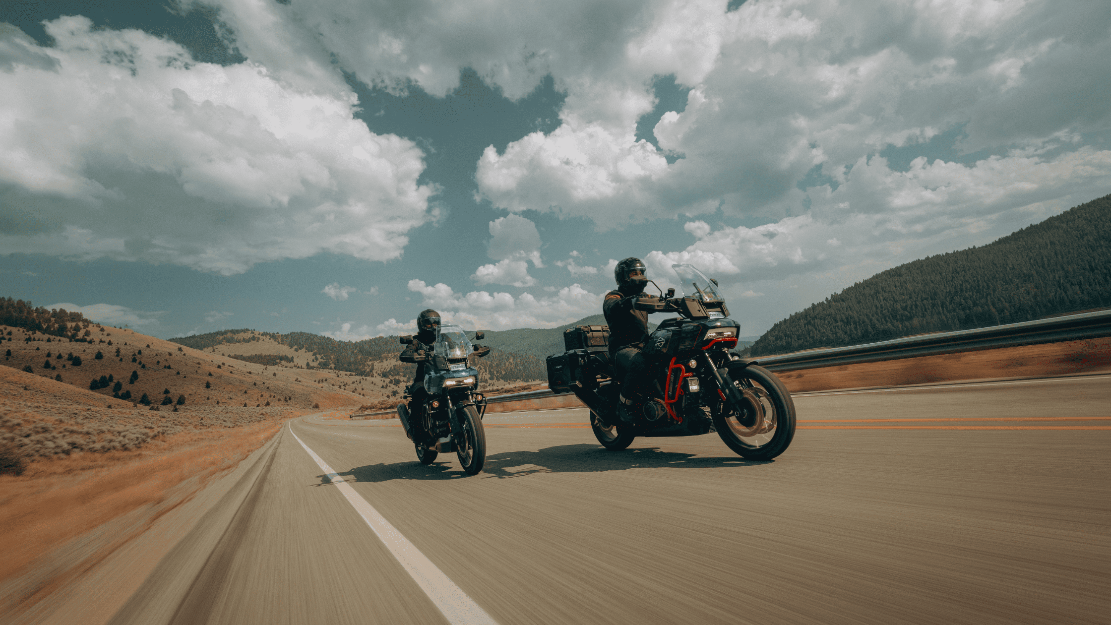 Two adventure motorcyclists riding through open scenic highways.