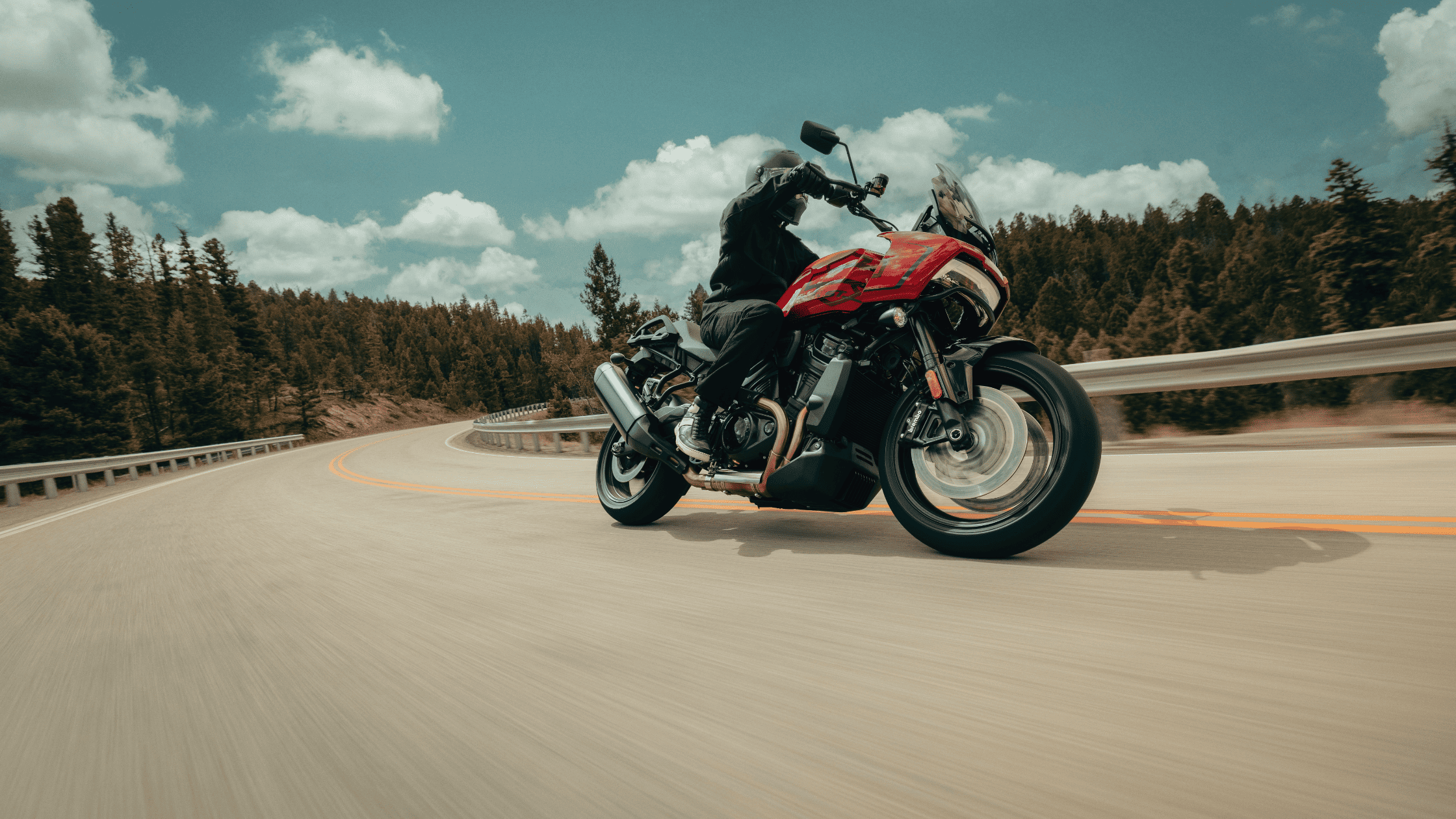 Motorcyclist leaning into a curve on a red adventure touring bike.