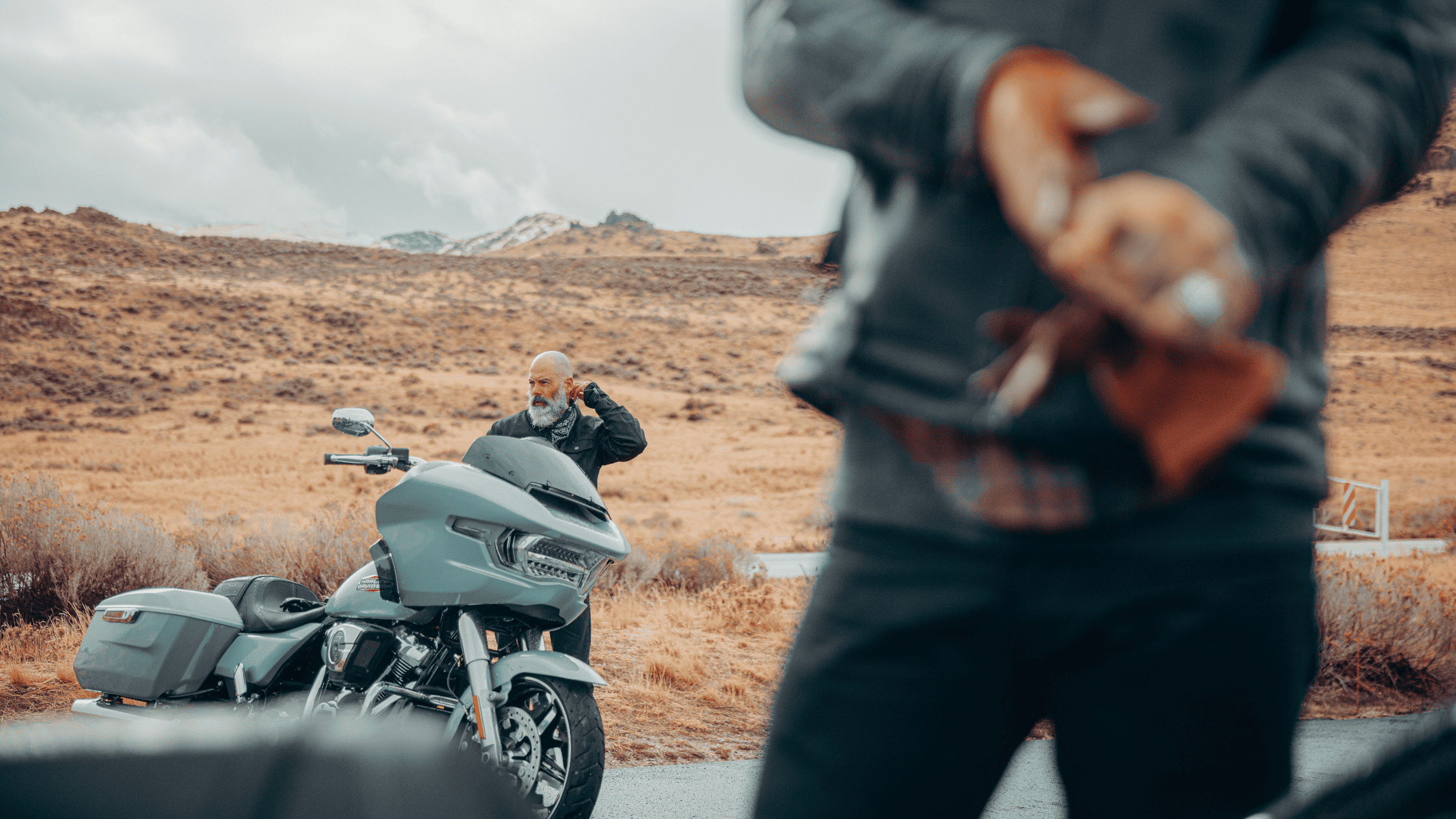 Motorcyclists preparing for a ride with a touring bike on roadside.