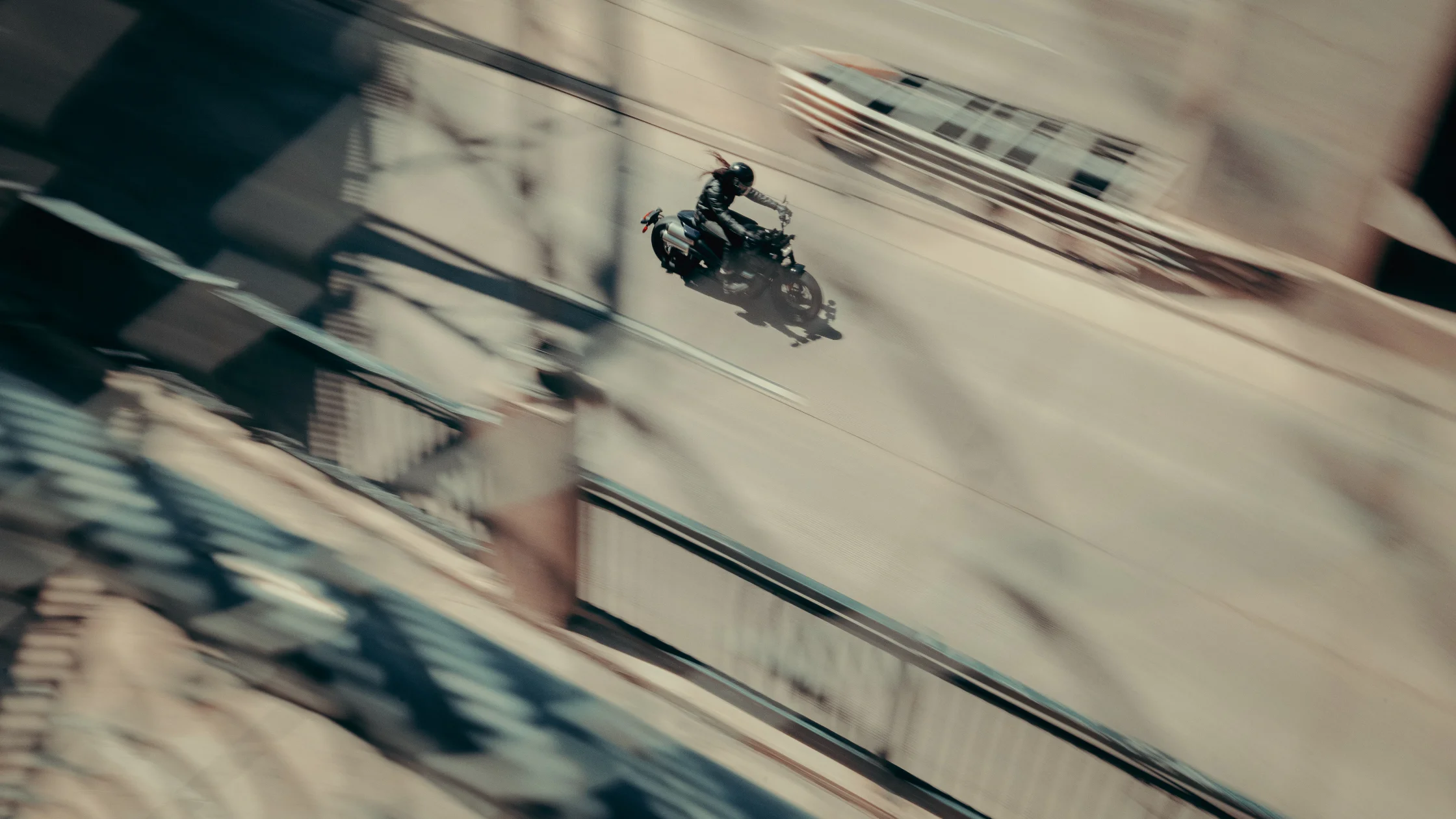 A motorcyclist rides the 2025 Harley-Davidson® Sportster S across an urban bridge, captured from a high-angle perspective.