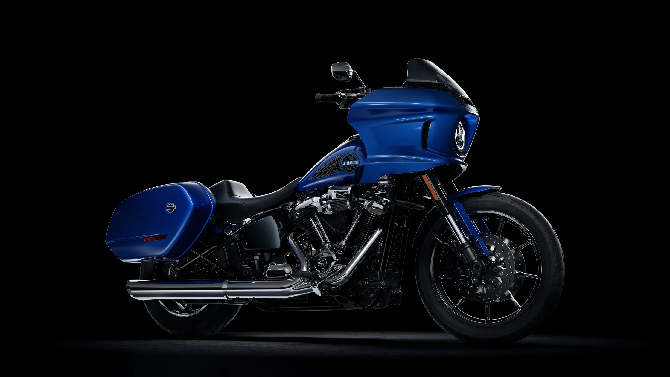 2025 Harley-Davidson® Low Rider ST in blue with saddlebags and fairing, dark background