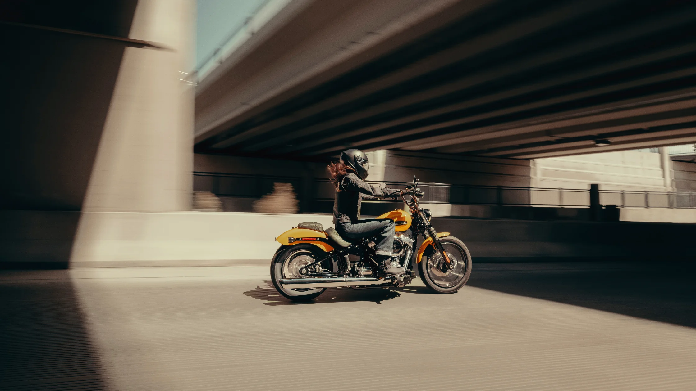 Rider on 2025 Harley-Davidson® Street Bob® in yellow speeding under a highway overpass.