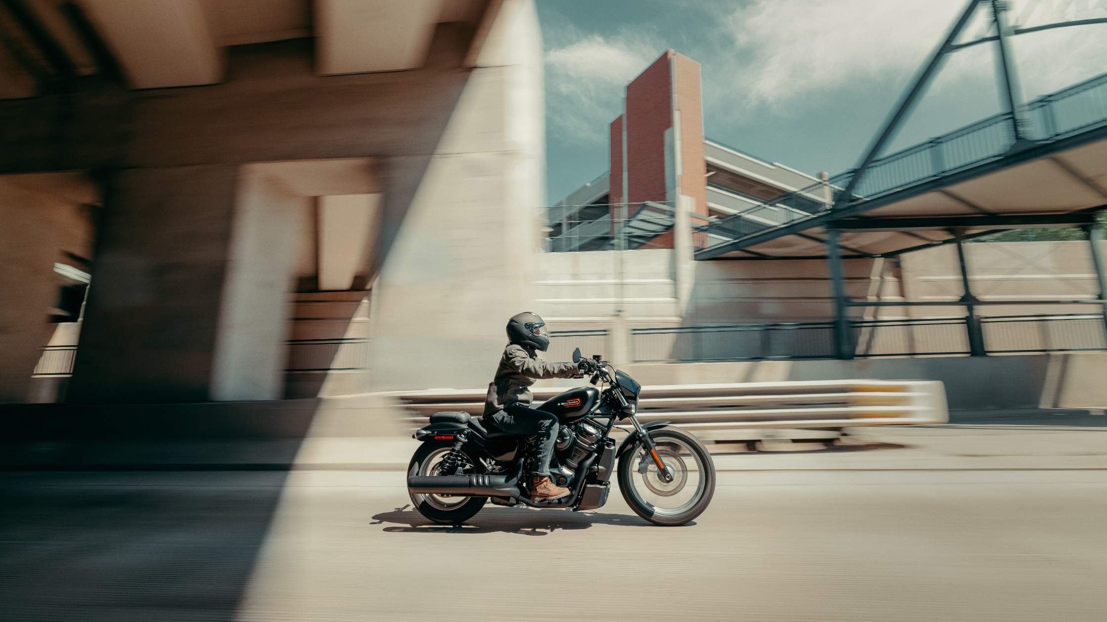 Rider on a 2025 Harley-Davidson® Nightster® S cruising under an urban overpass in the city