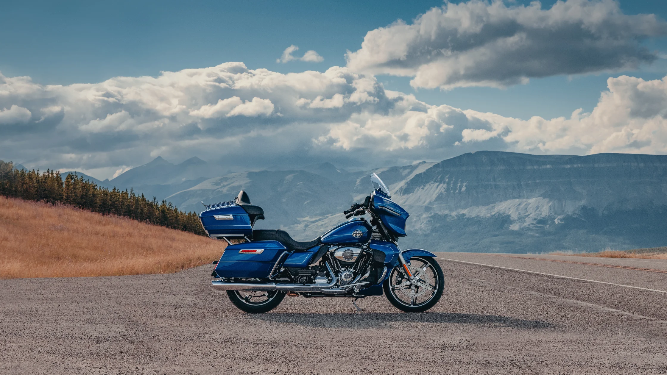 2025 Harley-Davidson Street Glide Ultra in blue parked on mountain road under cloudy sky