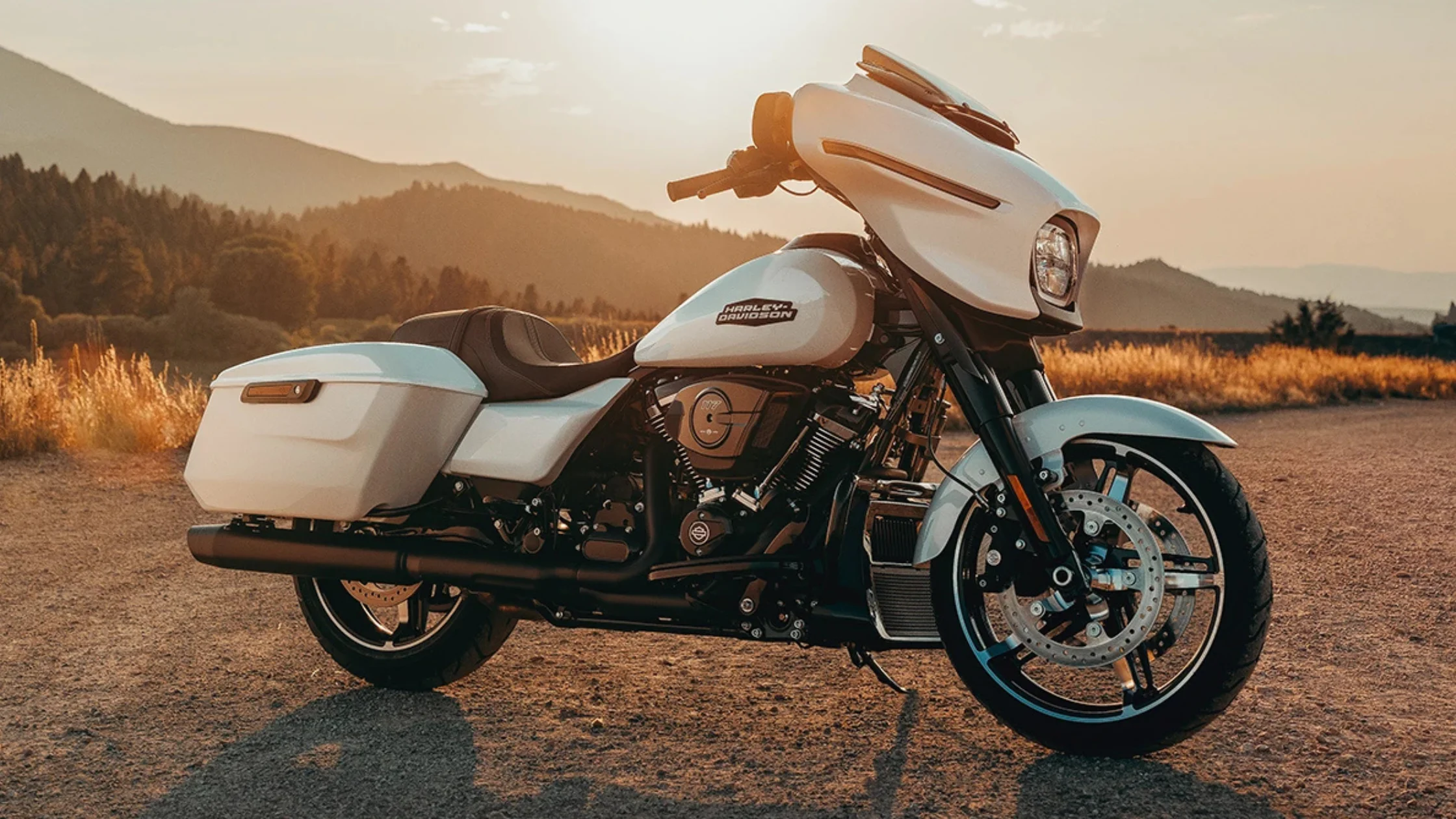 2025 Harley-Davidson® Street Glide® in white parked at sunset with mountain hills in the background