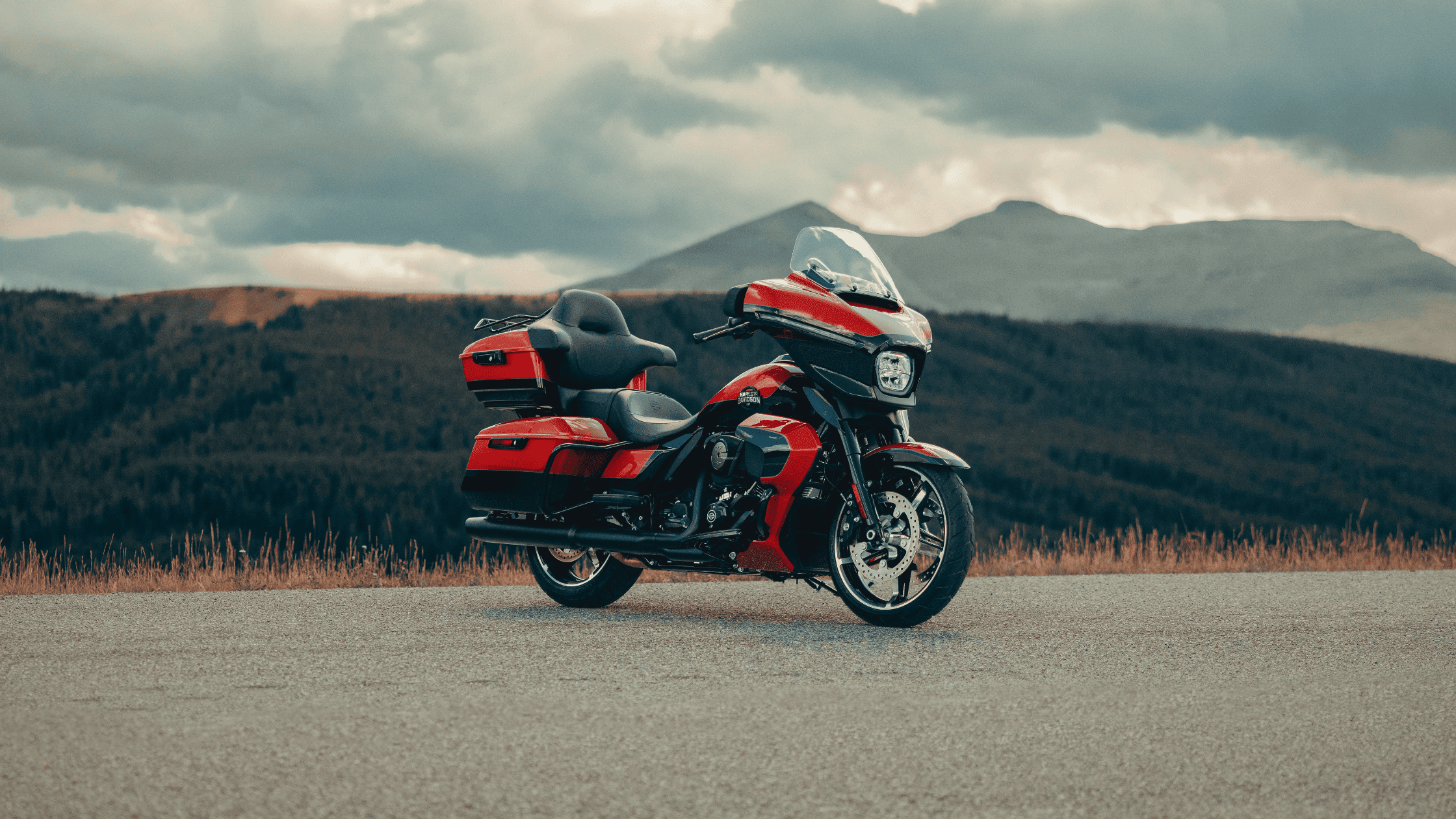 2025 Harley-Davidson® Street Glide® Ultra in red parked on a mountain overlook with scenic forest views