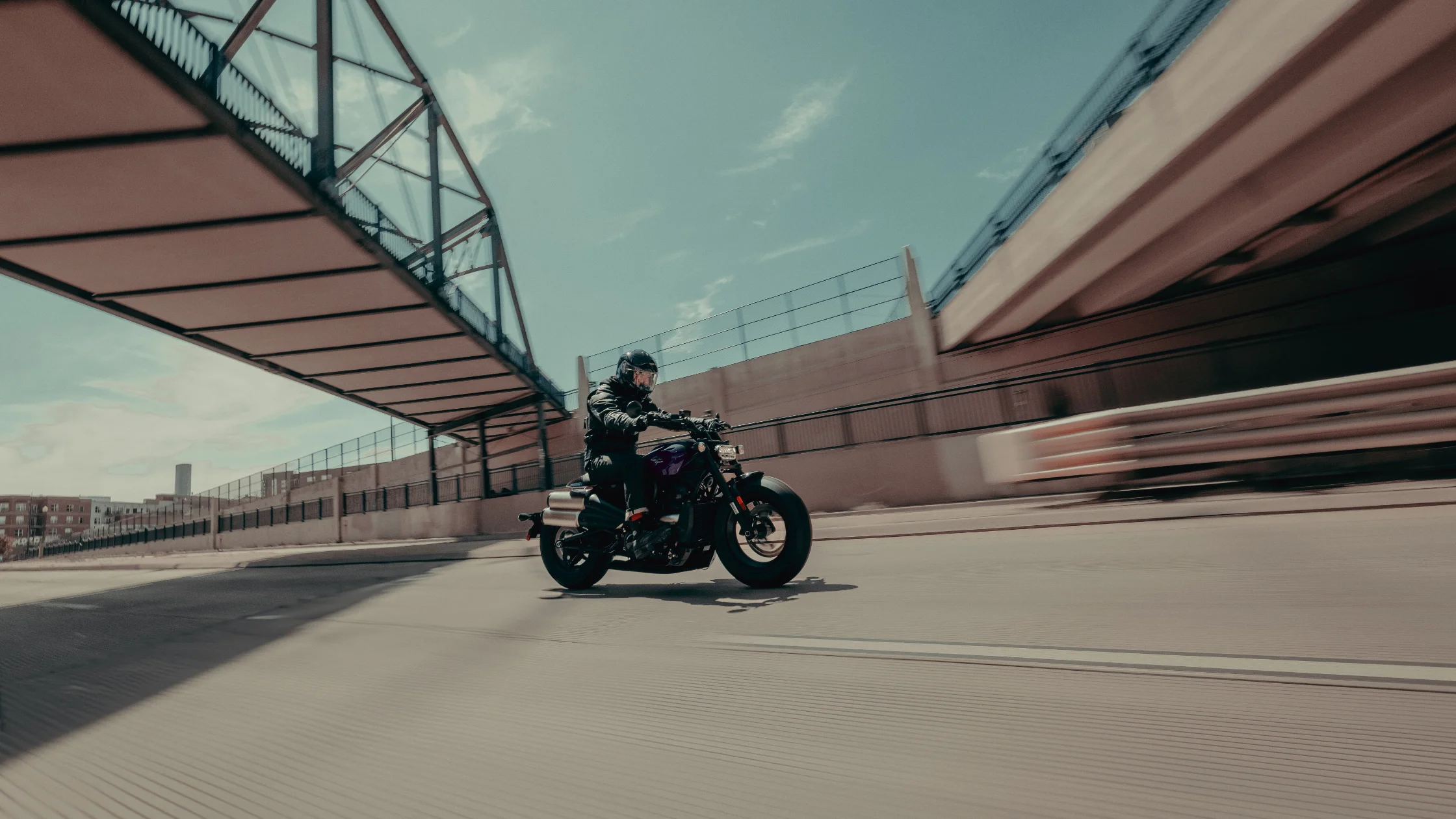 2025 Harley-Davidson® Sportster® S cruising under an urban bridge with rider in full gear.