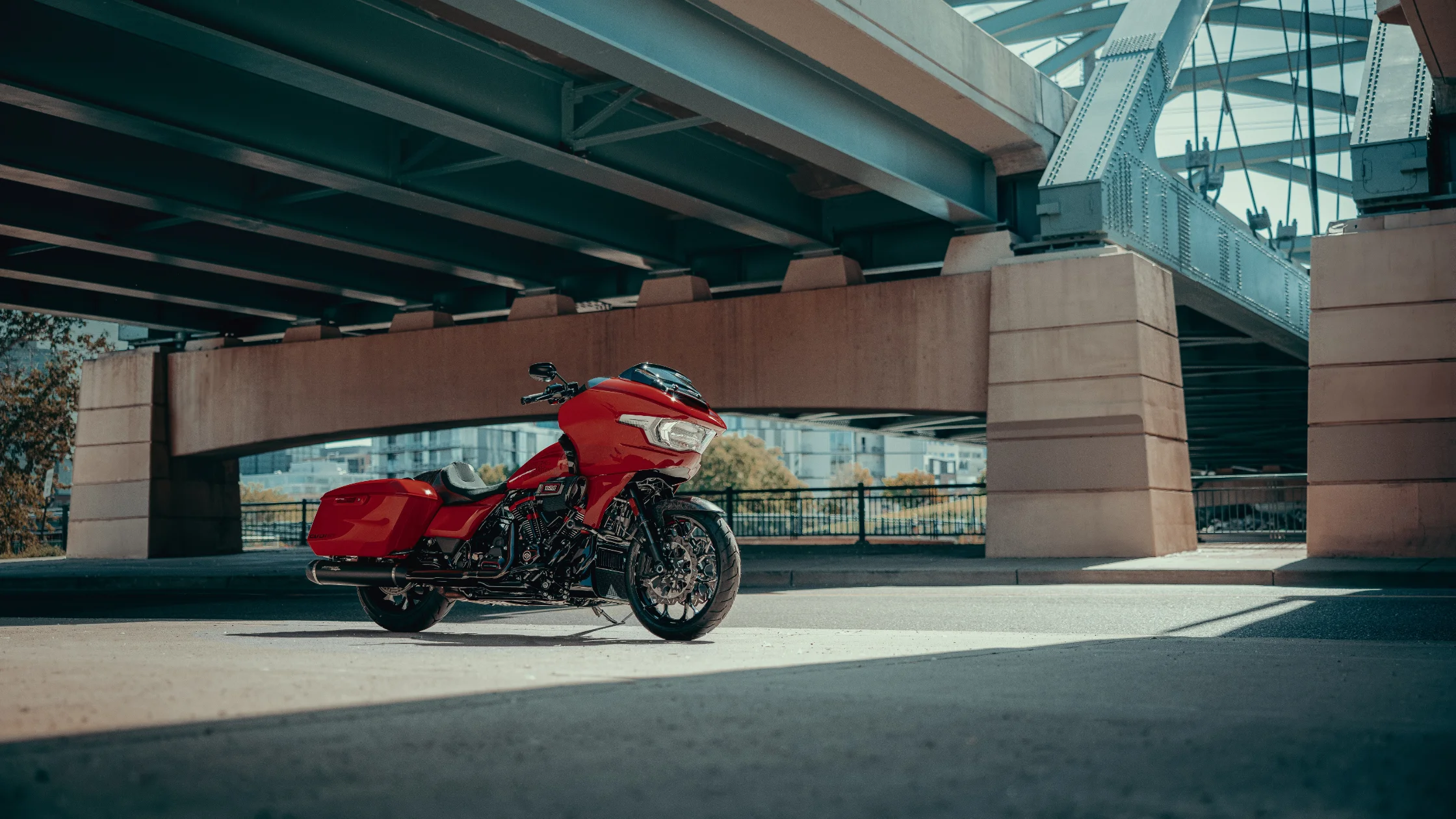 2025 Harley-Davidson® CVO™ Road Glide® ST in red parked under urban bridge with modern city backdrop.