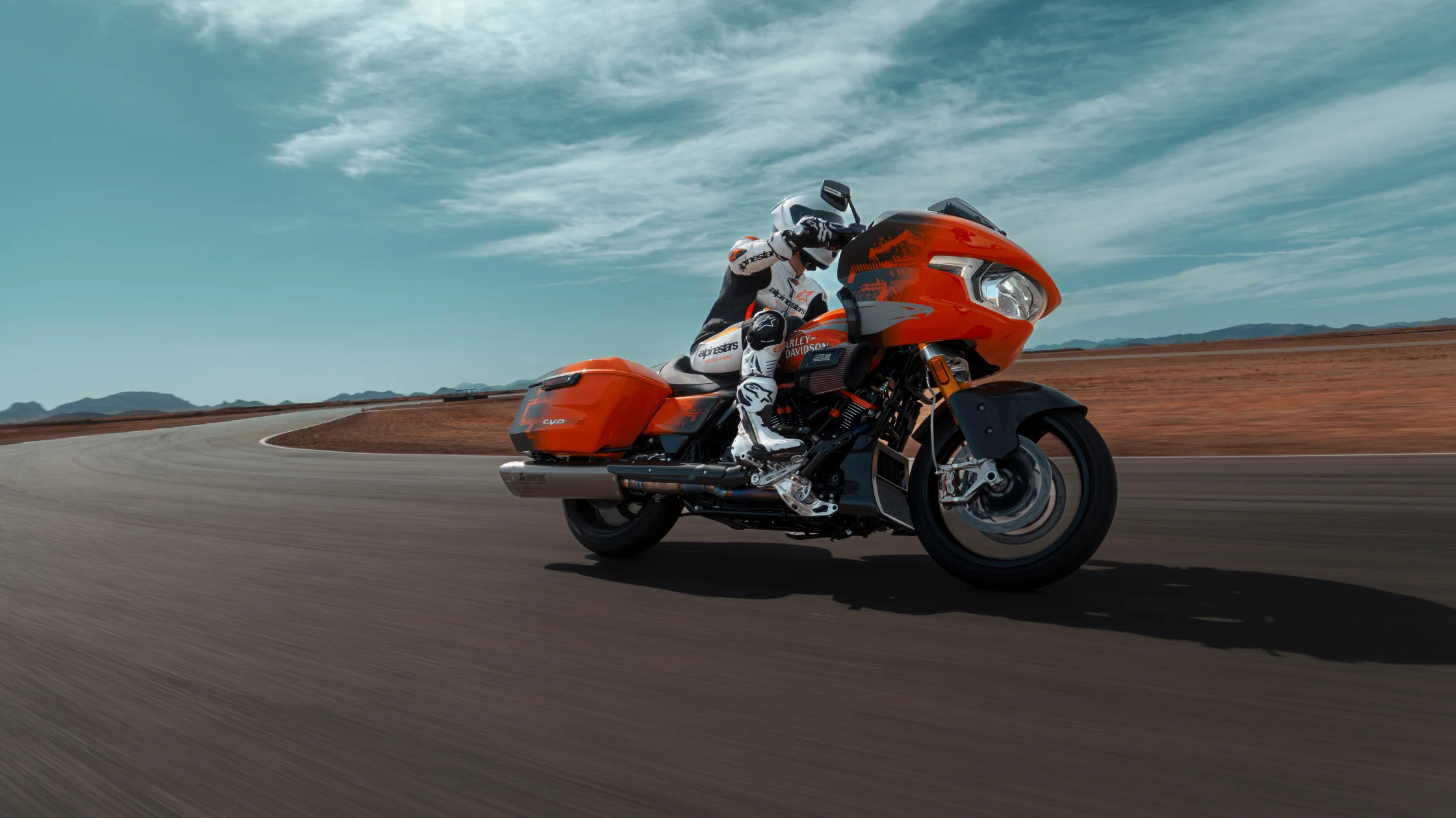 2025 Harley-Davidson® CVO™ Road Glide® RR in orange racing down track with rider in full gear.