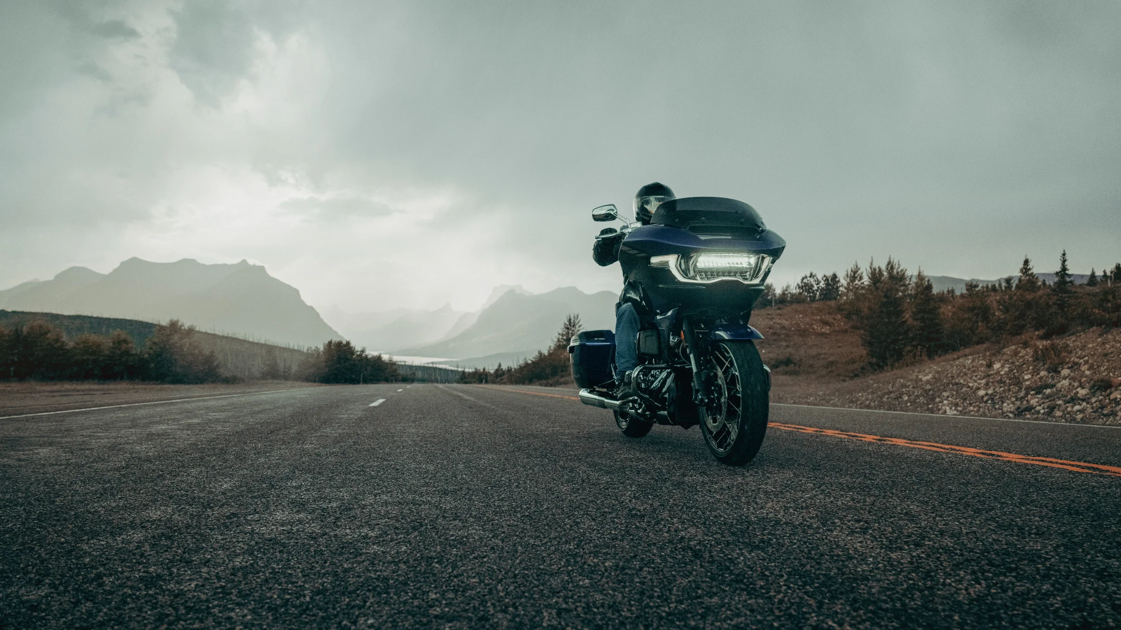 2025 Harley-Davidson® CVO™ Road Glide® cruising on an open mountain highway under moody skies.