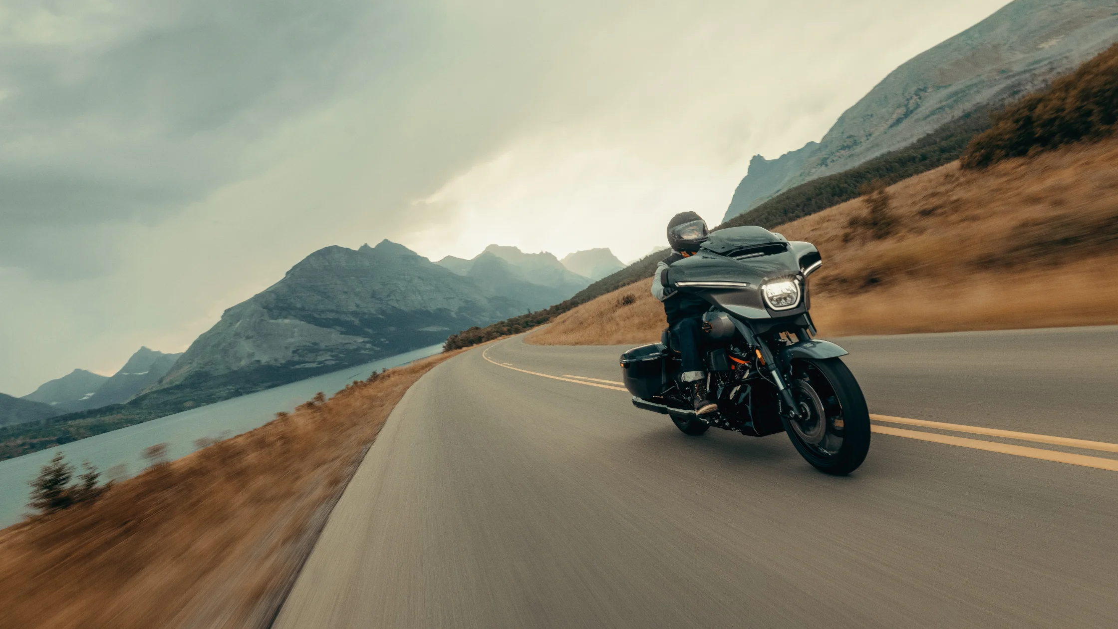 2025 Harley-Davidson® CVO™ Street Glide® riding along a scenic mountain road near a lakeside curve.
