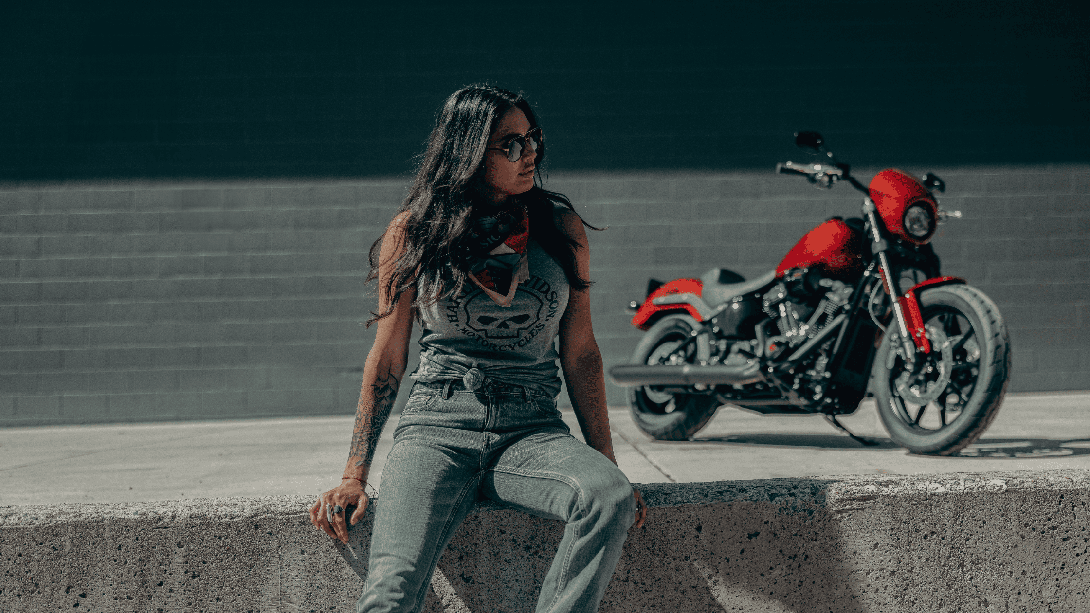 Woman in casual riding gear sitting in front of a red 2025 Harley-Davidson Low Rider S motorcycle.