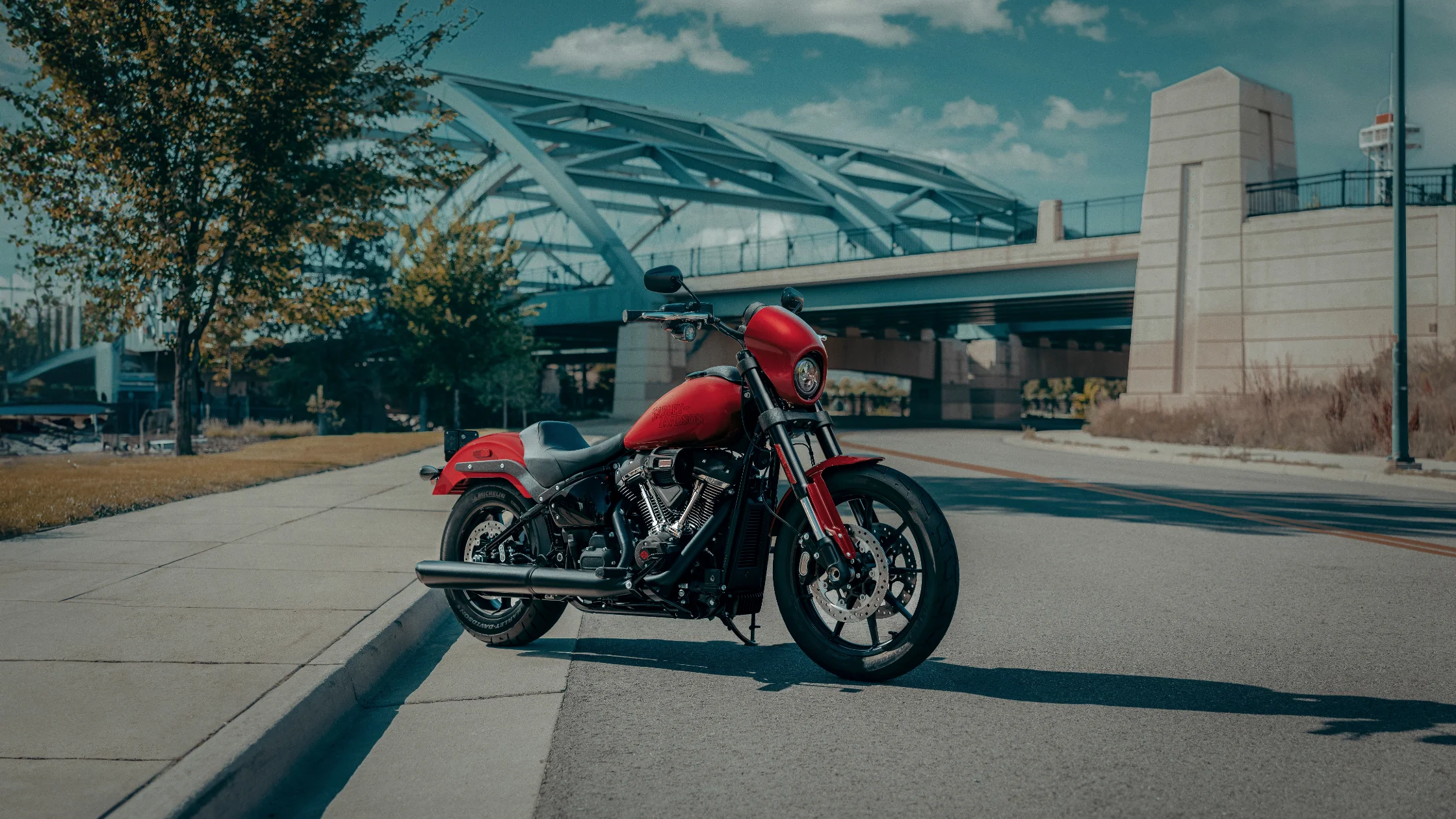 2025 Harley-Davidson Low Rider S parked on a city street with a bridge and modern buildings in the background.