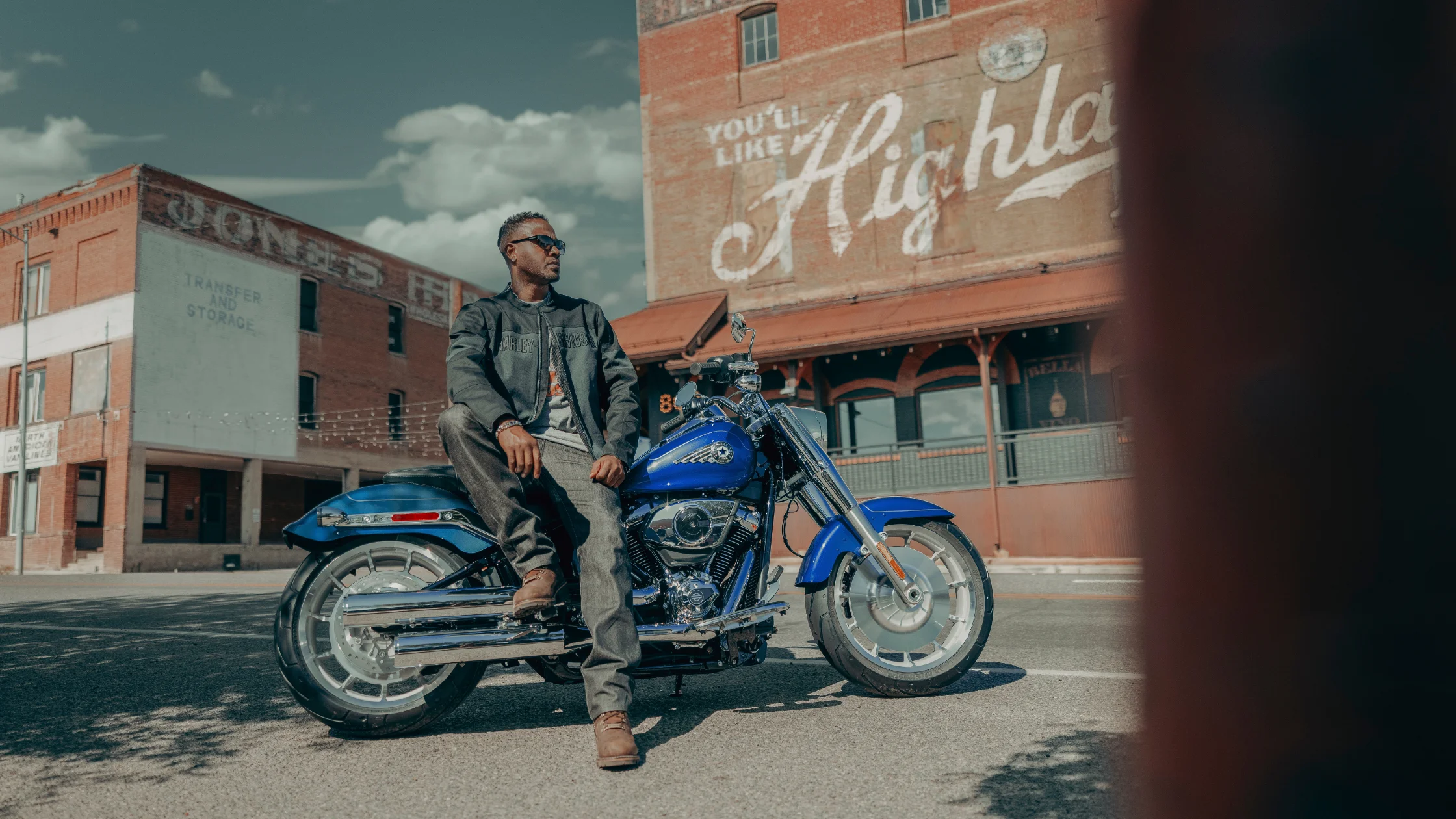 Rider sitting on a 2025 Harley-Davidson Fat Boy near Lynn Haven FL with historic brick buildings in the background.