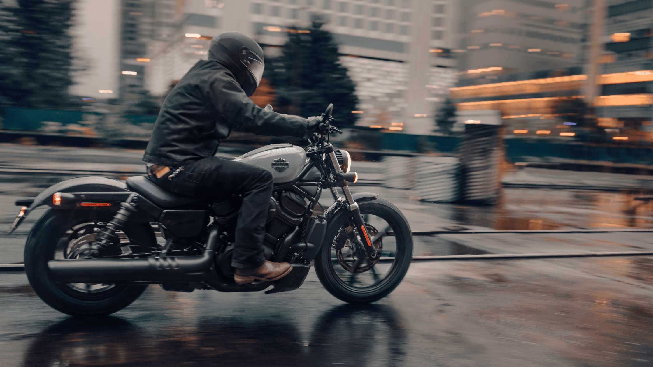Rider speeding through a rainy city on a 2025 Harley-Davidson Nightster motorcycle.