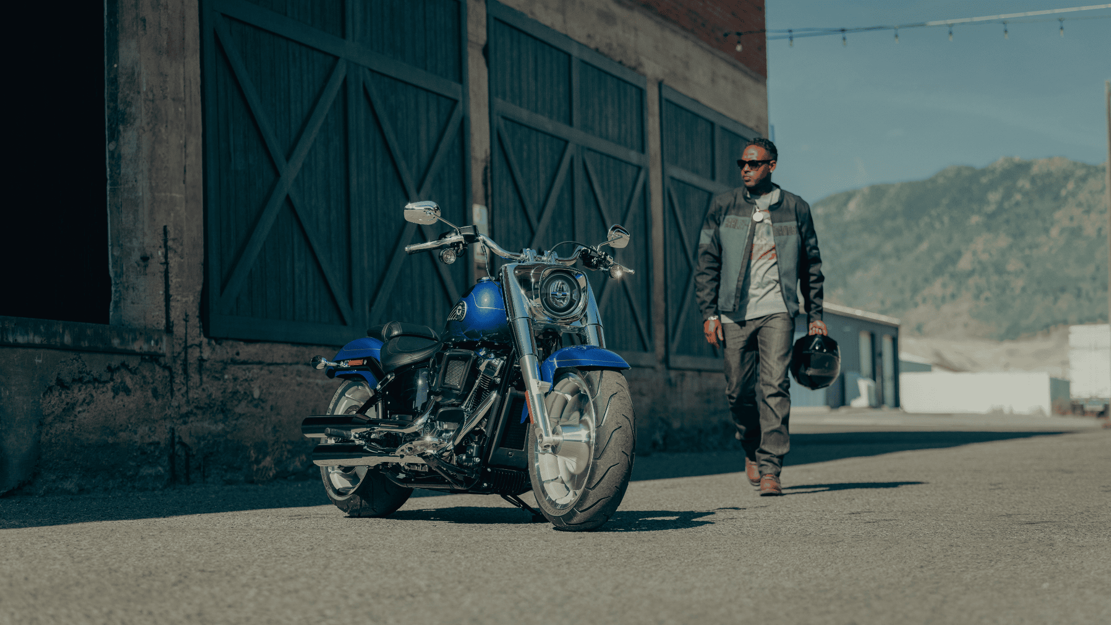 2025 Harley-Davidson Fat Boy parked on a quiet alleyway as a rider approaches.