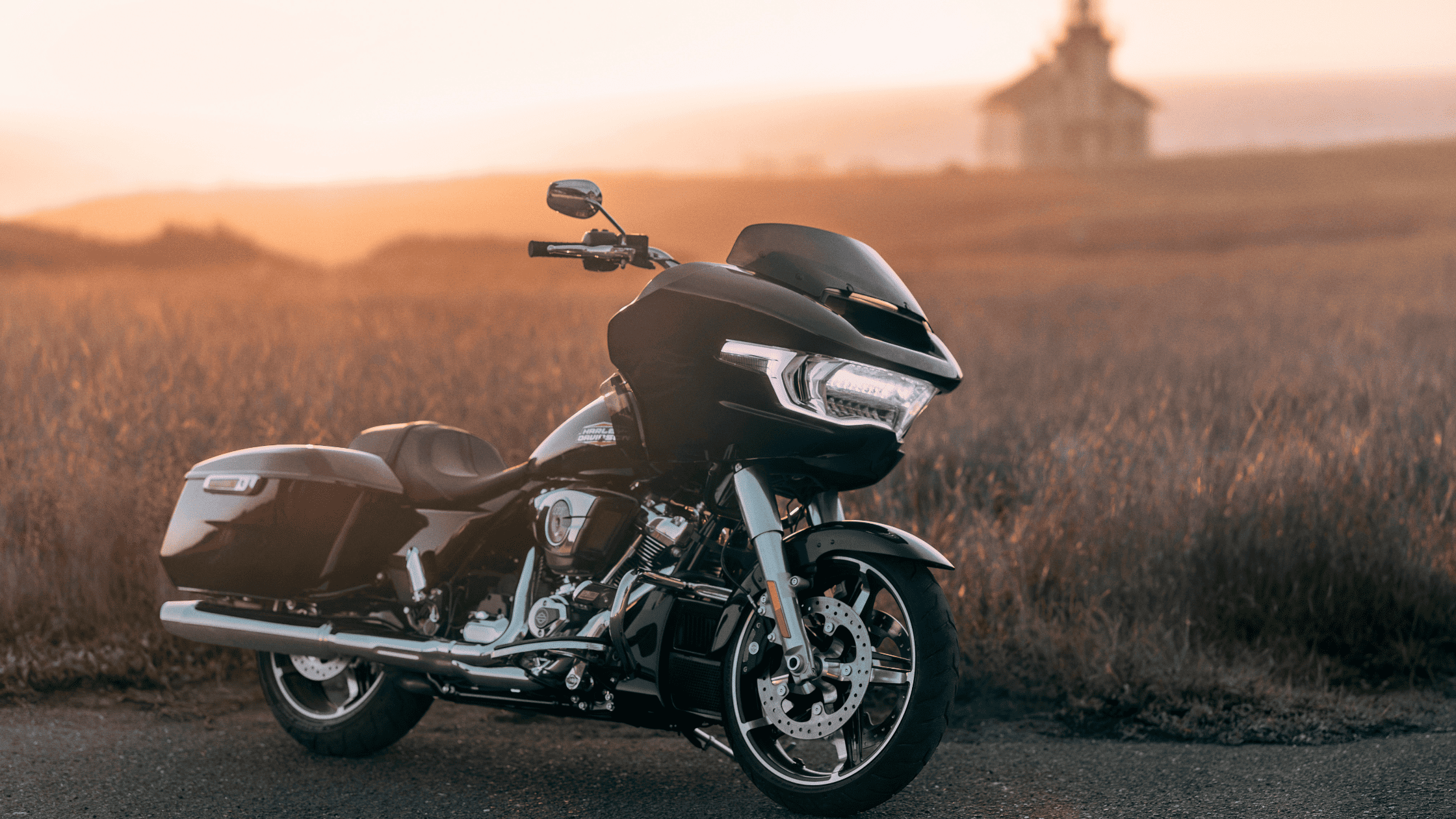2025 Harley-Davidson Road Glide parked in a golden field at sunset with a chapel behind.