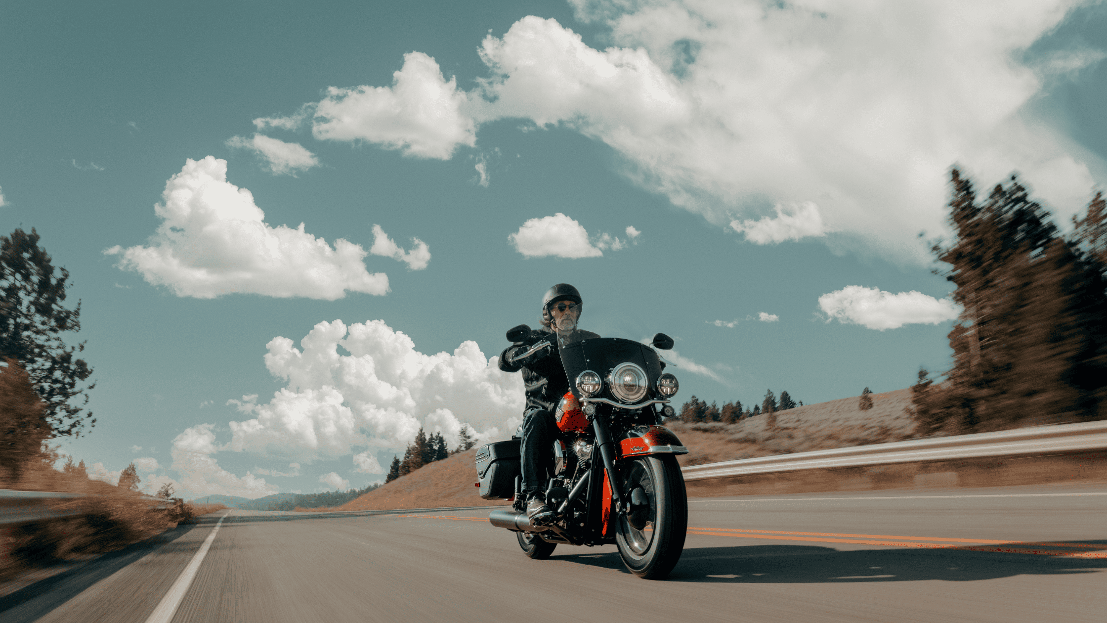 Rider on a 2025 Harley-Davidson Heritage Classic cruising along a winding highway.