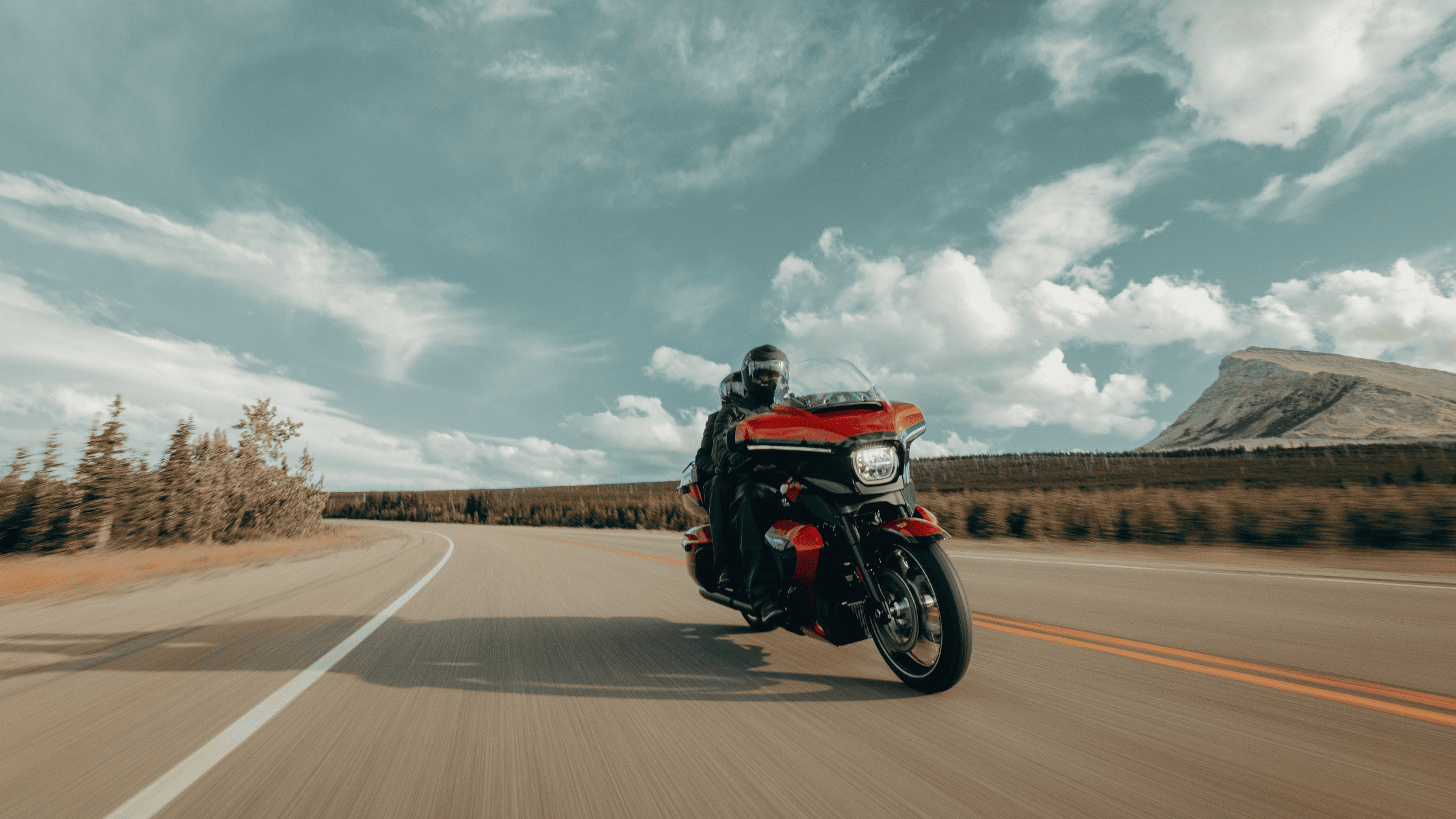 Two-up riders on a 2025 Harley-Davidson Street Glide Ultra in red cruising wide open highway.