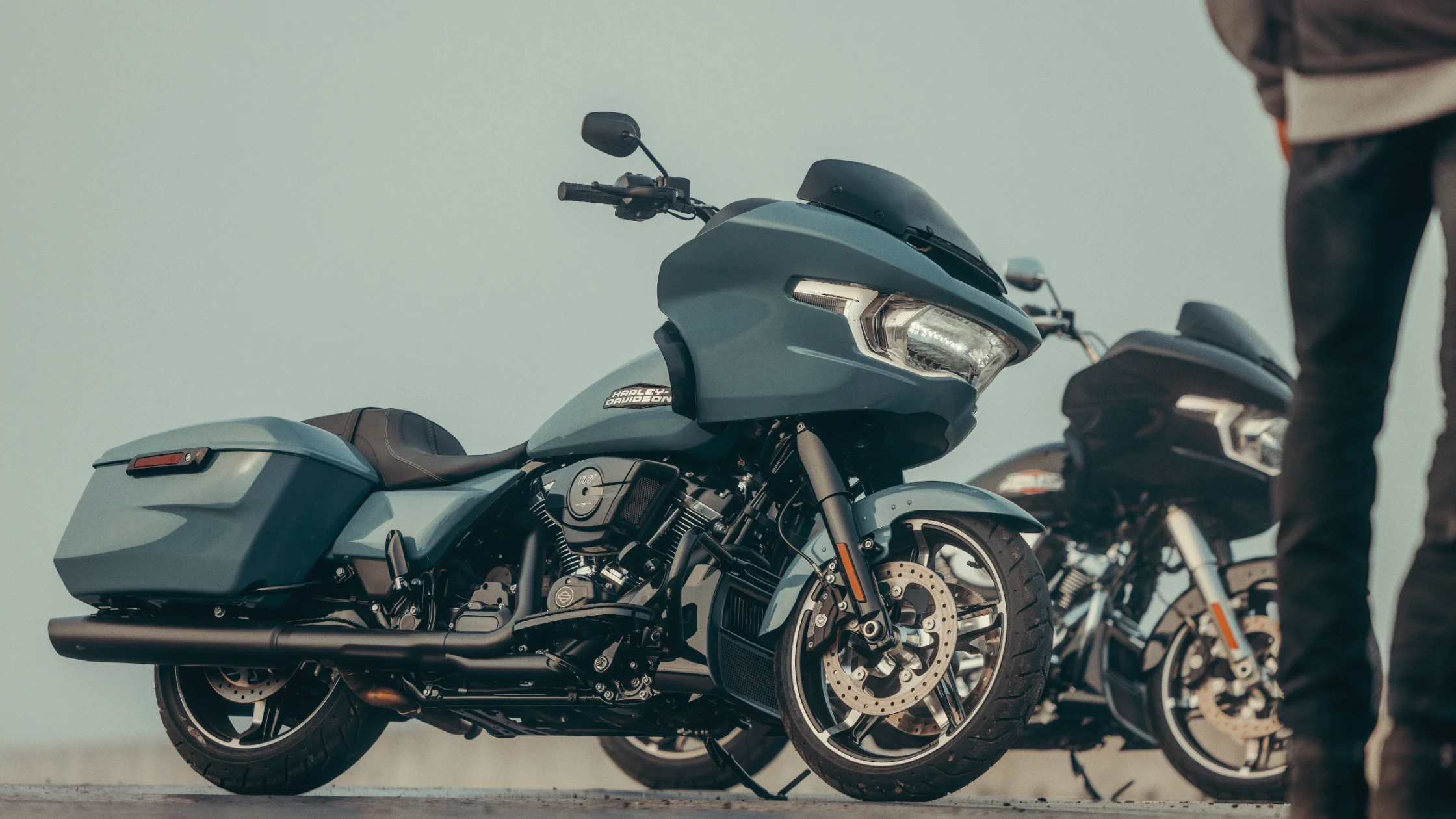 Matte blue 2025 Road Glide with LED headlamp and blacked-out engine parked roadside beside another bike.