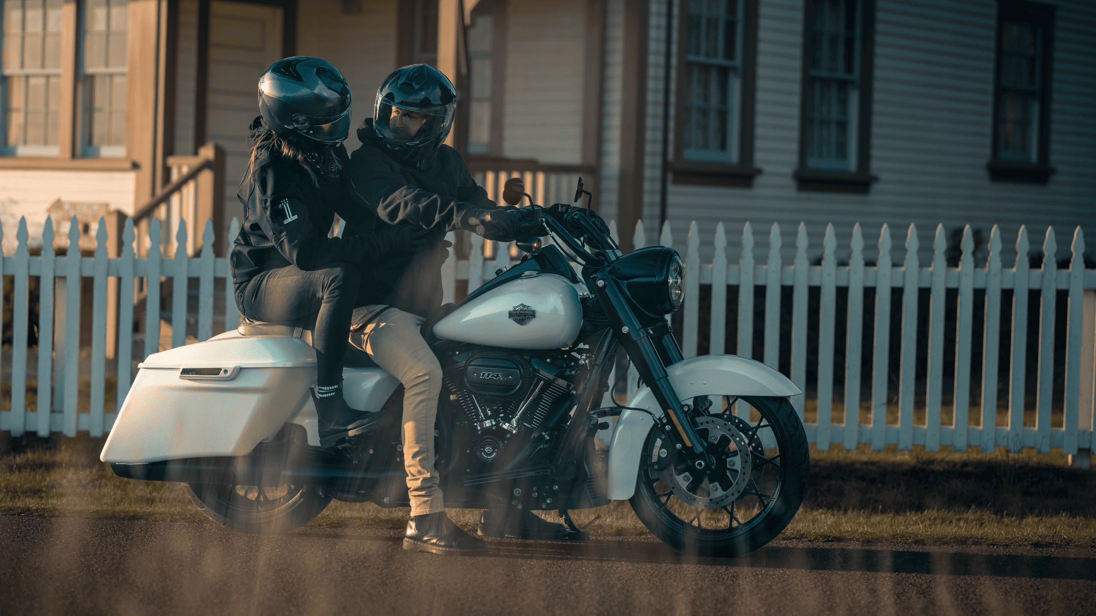 Two riders on white 2025 Harley-Davidson Road King Special near white picket fence