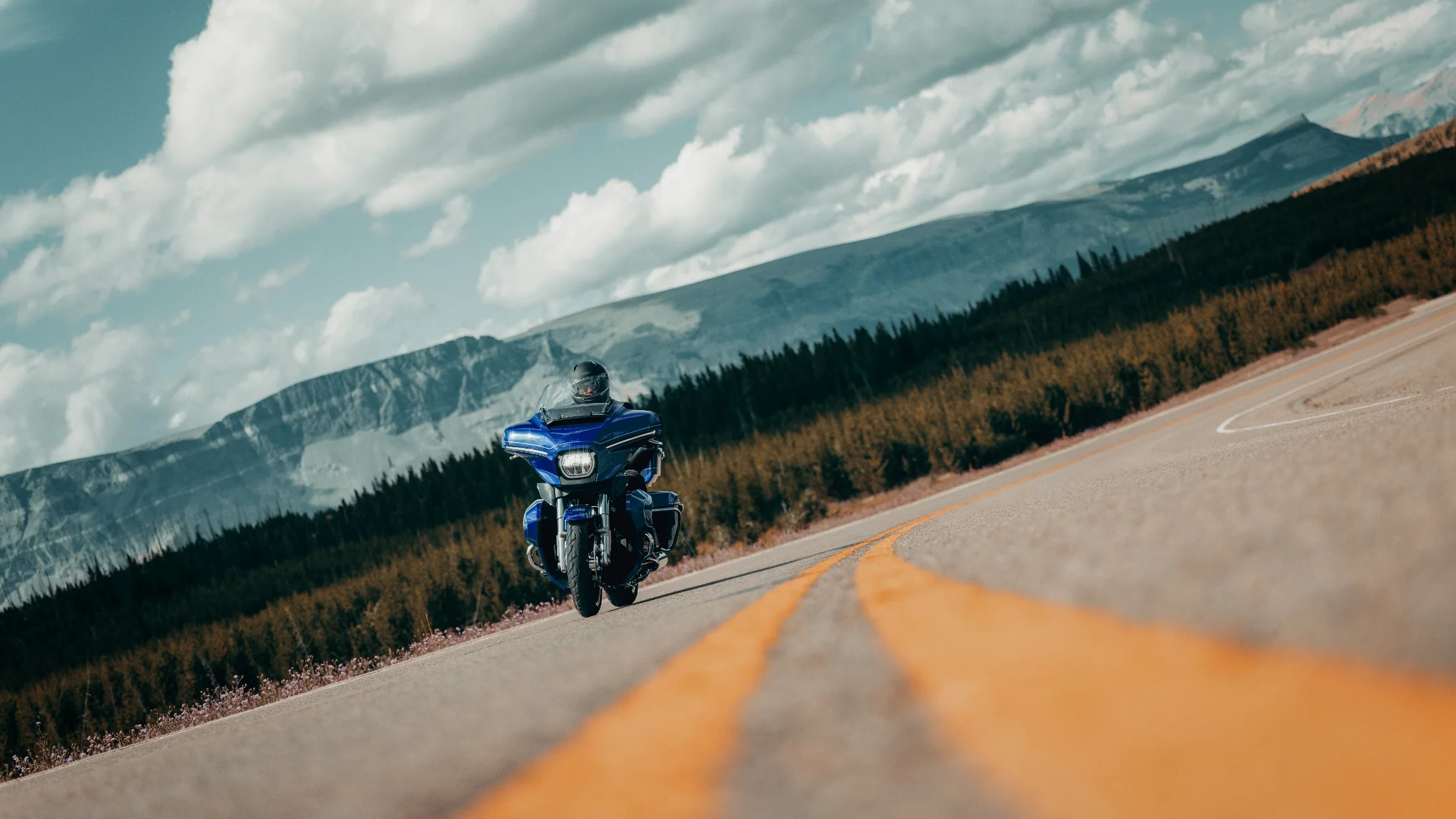 2025 Harley-Davidson® Street Glide® Ultra seen from rear on highway with mountain scenery ahead.