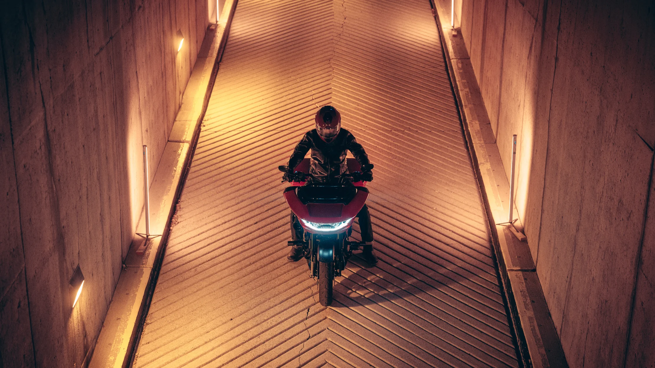 2025 CVO Road Glide ST in red viewed head-on in tunnel with rider wearing helmet and jacket.