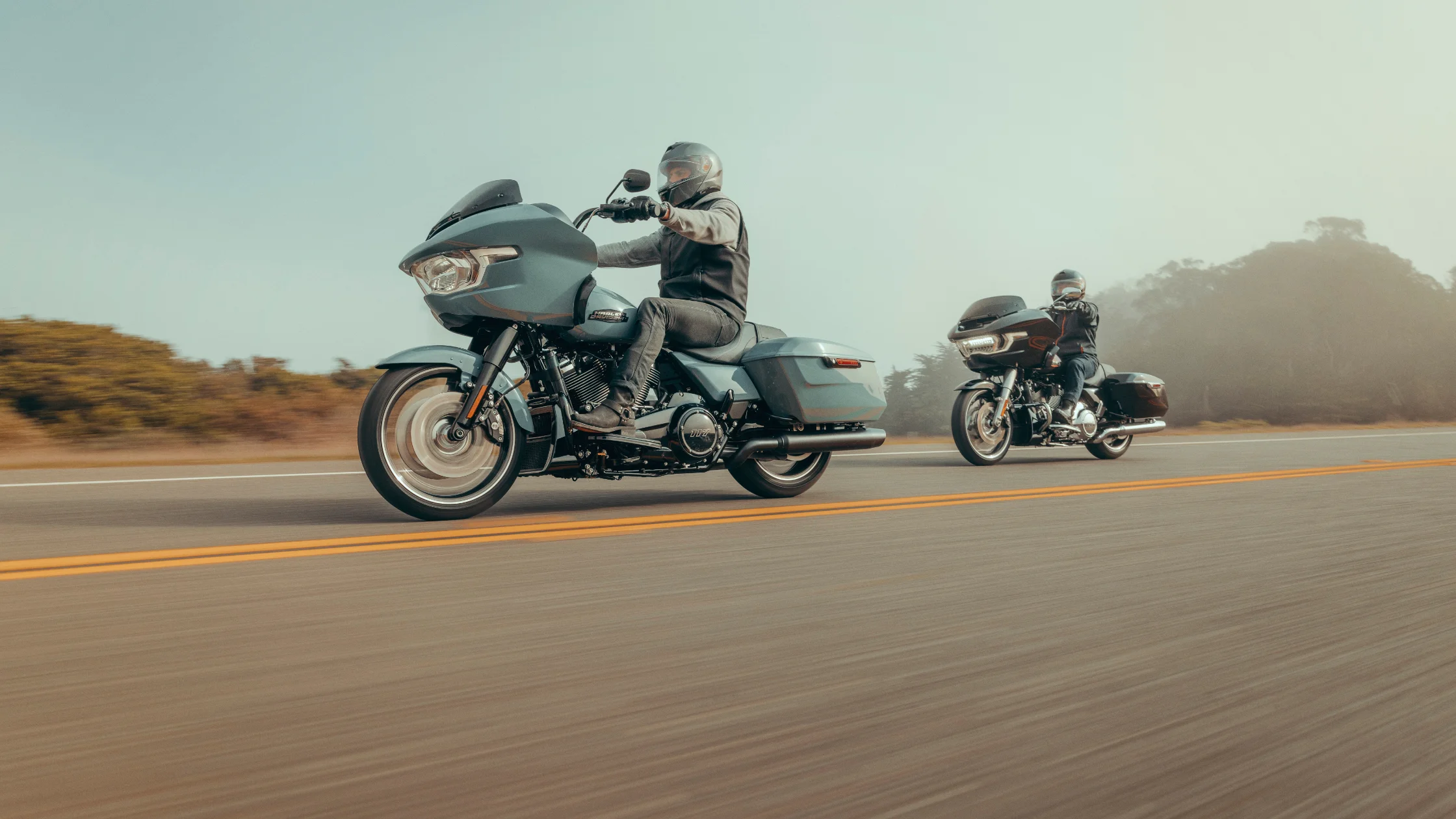 Two 2025 Road Glide motorcycles on highway, side view of riders cruising during daylight.