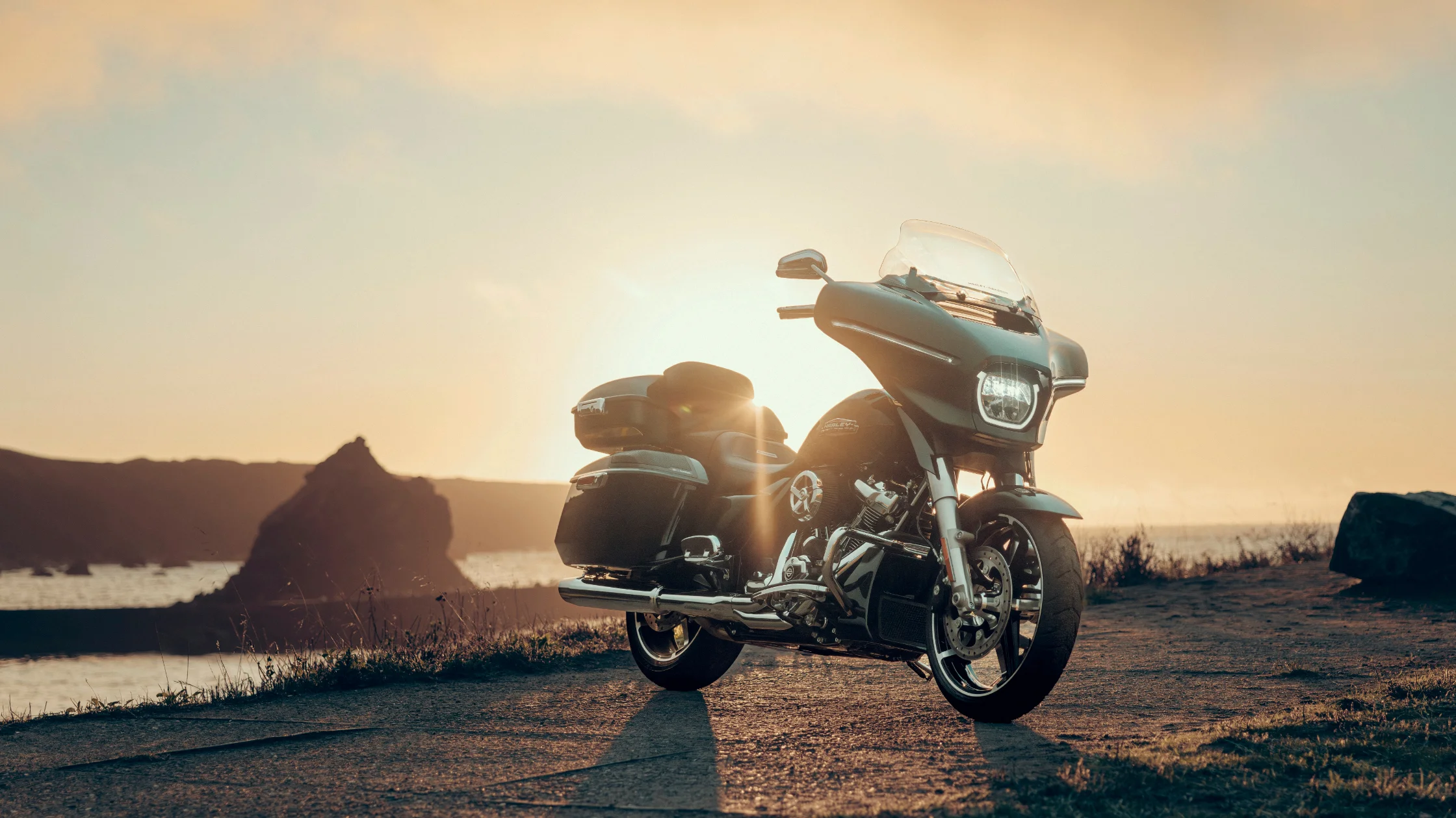 2025 Street Glide parked by ocean cliff at sunset, showing touring pack and front fairing.