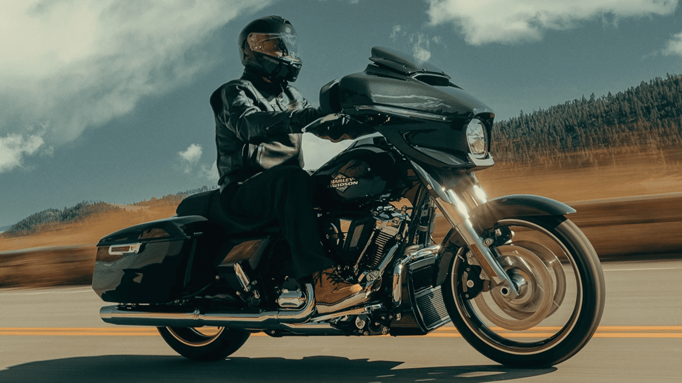 Rider cruising a 2025 Harley-Davidson® Street Glide® on an open highway near Atlanta, GA, showcasing its sleek touring design and dynamic ride modes.
