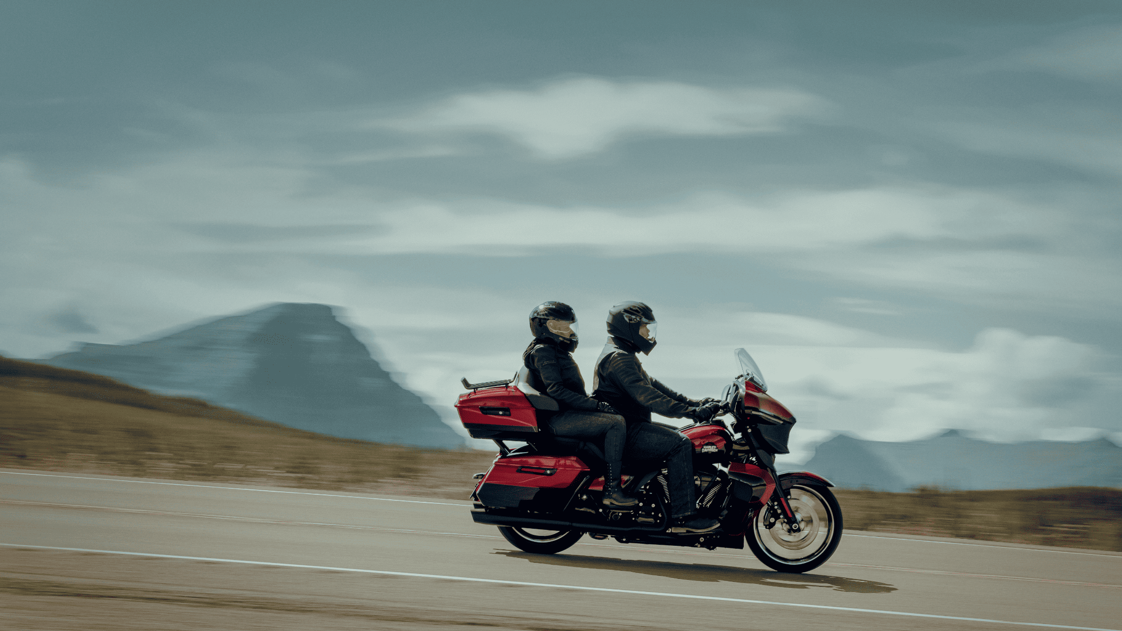 Two-up riders on a 2025 Harley-Davidson® Street Glide® Ultra touring bike in red, riding along scenic mountain roads near Covington, GA.