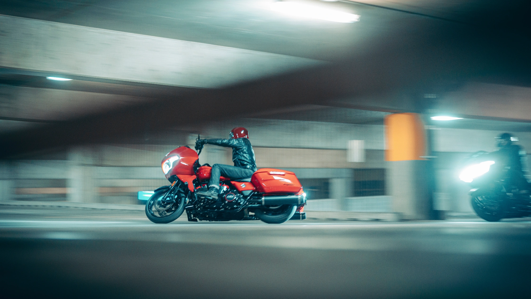 Rider on 2025 CVO Road Glide ST in red, cruising through a dimly lit parking structure at speed.
