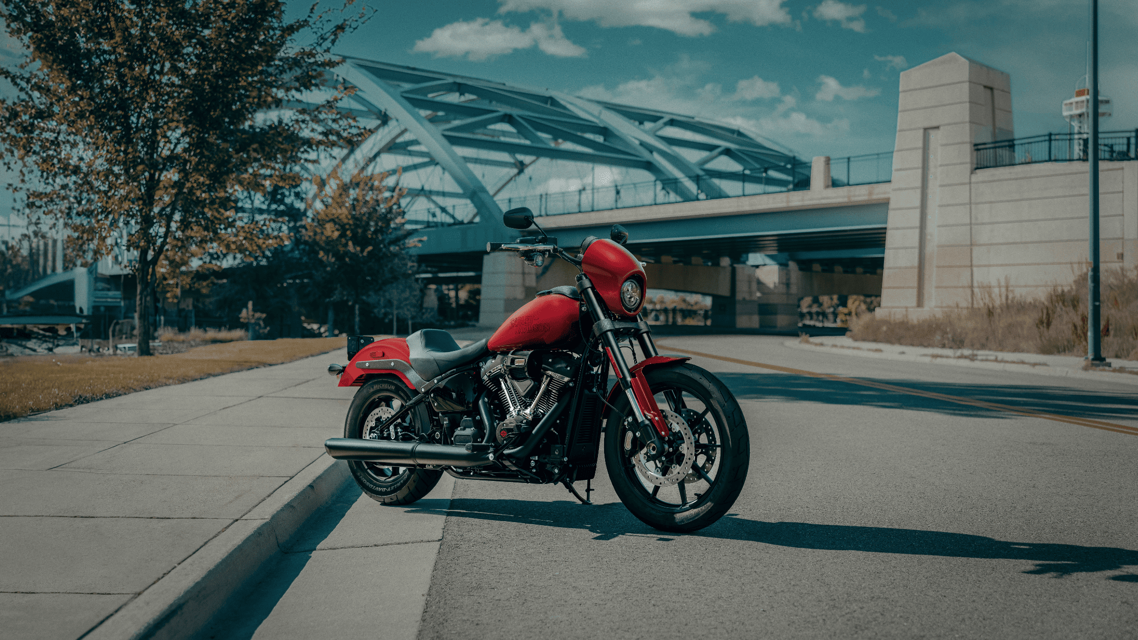 2025 Low Rider S motorcycle in bold red parked near modern bridge with urban backdrop