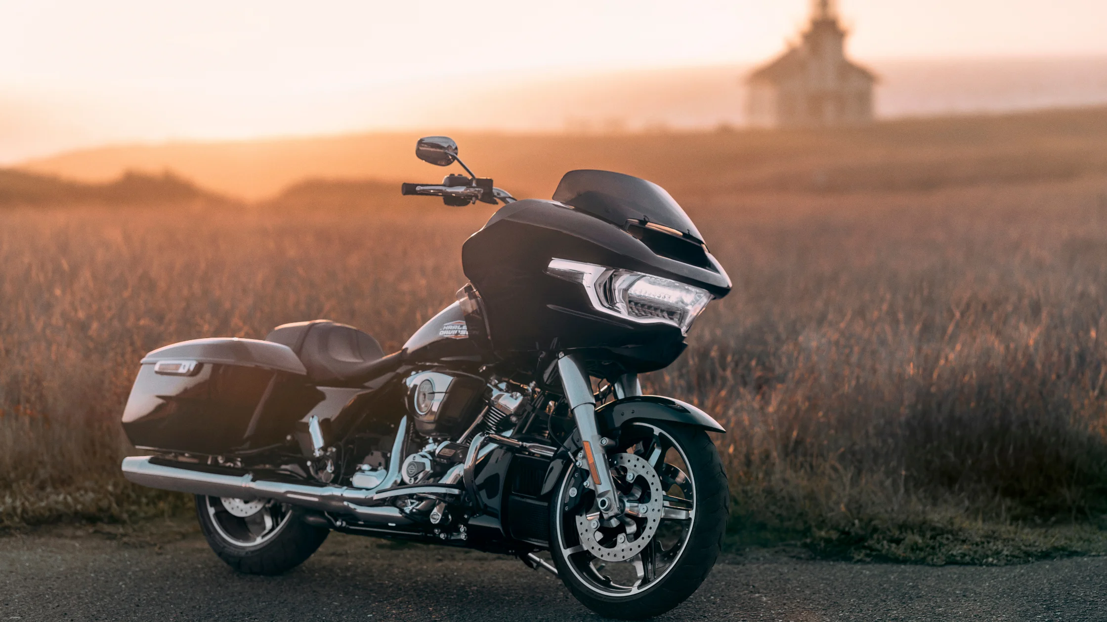 2025 Road Glide Carryover motorcycle in black parked on open road at sunset with warm lighting.