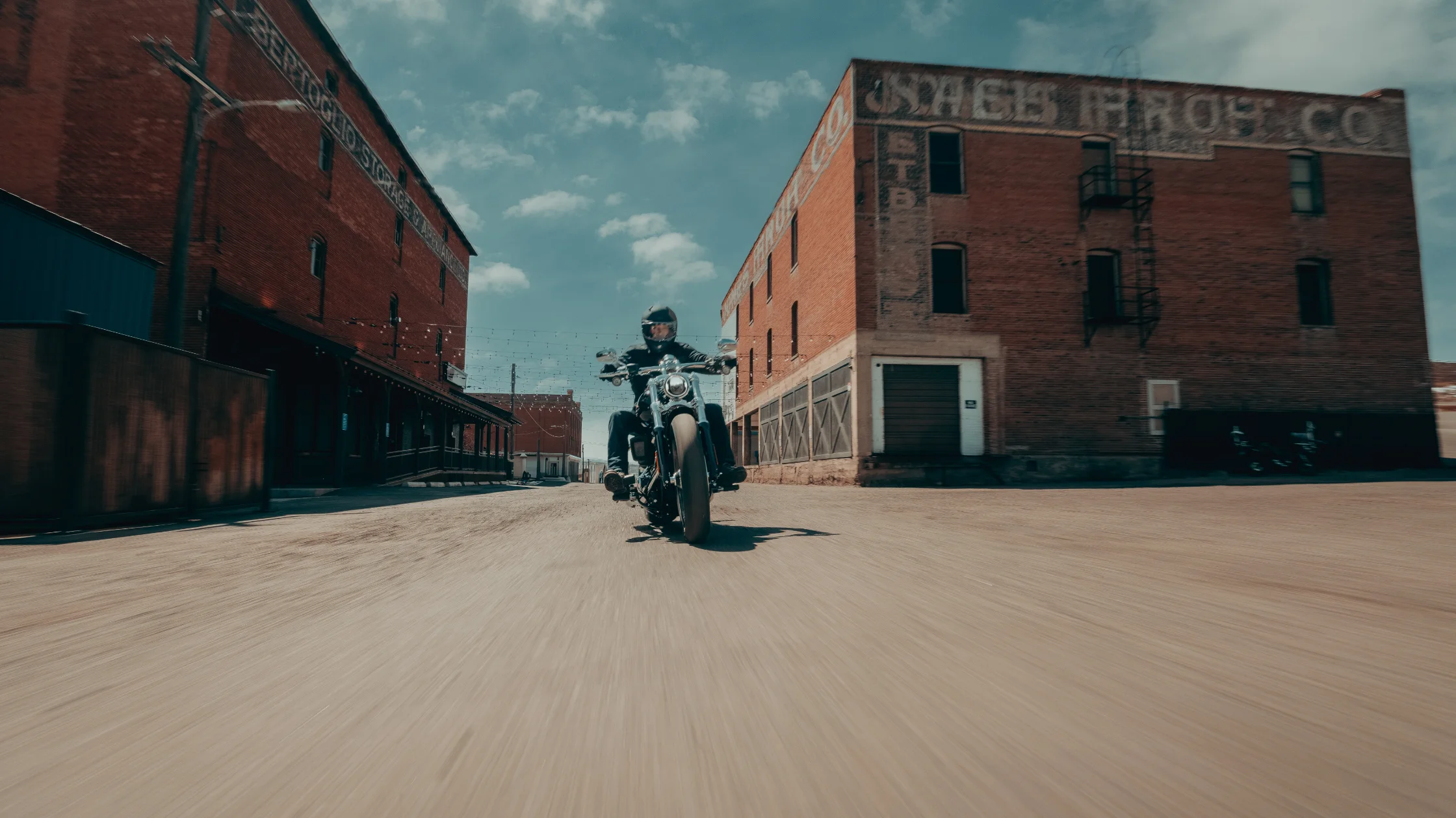 2025 Breakout motorcycle ridden through a historic brick district, highlighting its chrome finish and wide tires.