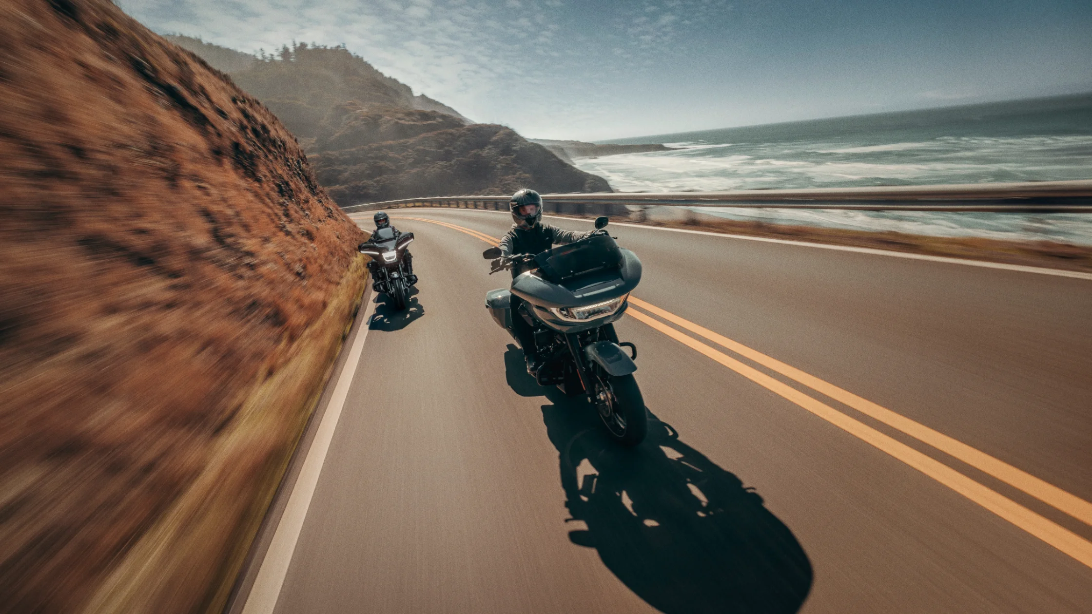 2025 Road Glide Carryover models cruising on a scenic coastal highway with ocean cliffs in the background.