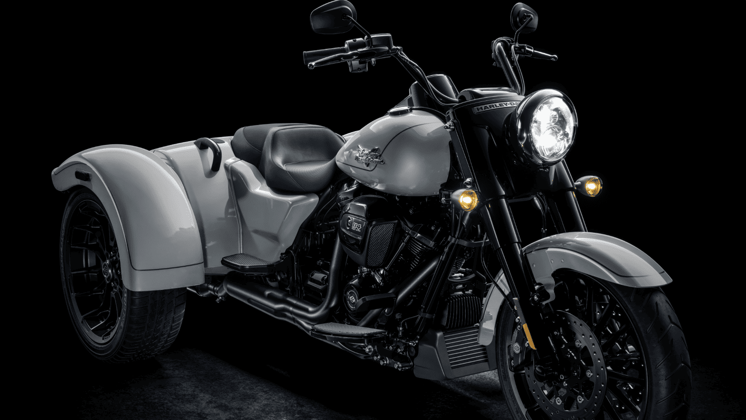 Close-up of the 2025 Harley-Davidson® Freewheeler® in a dark showroom setting, showcasing its trike design and aggressive stance near Sanford, FL.