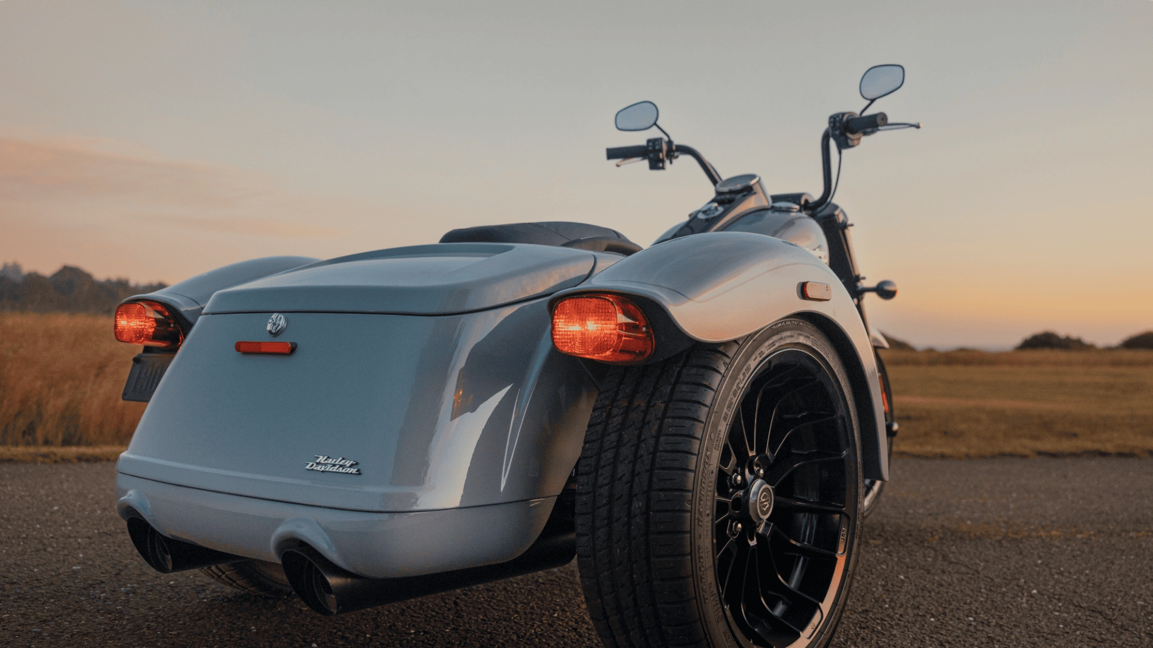 Rear view of a 2025 Harley-Davidson® Freewheeler® parked at sunset near Bentonville, AR, showing classic trike styling and rear lighting.