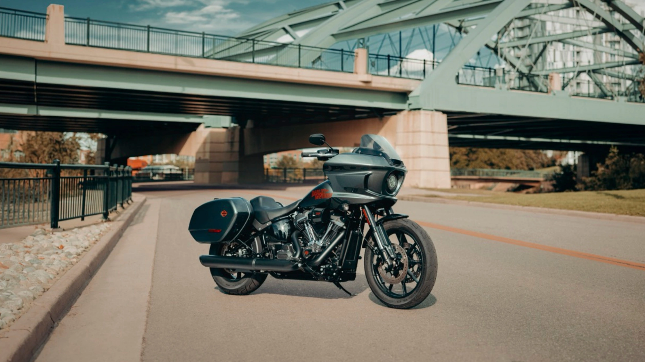 2025 Harley-Davidson® Low Rider® ST positioned under a bridge, emphasizing its aerodynamic fairing, saddlebags, and aggressive West Coast styling with performance-focused detailing.
